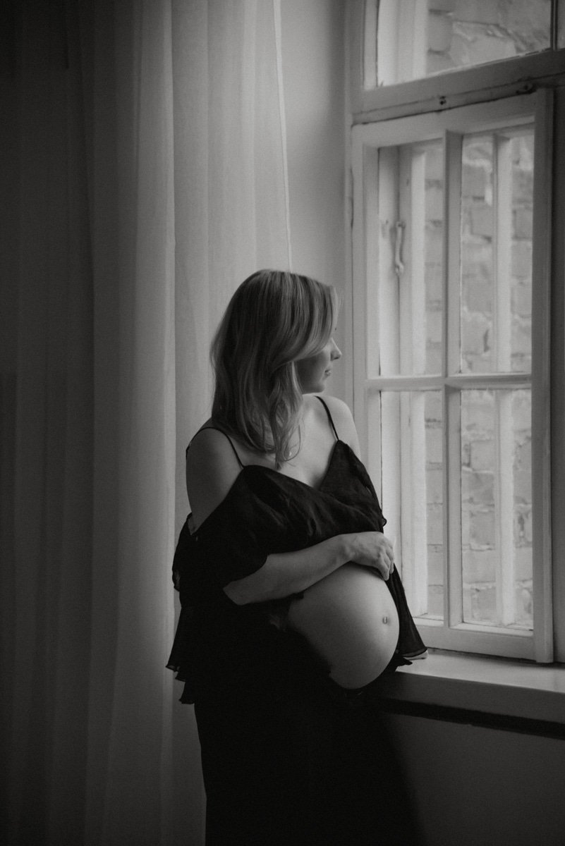 Raskaana oleva pitää kättään vatsan päällä. Odotusajankuvaus Heidi Väisäsen studiolla Keravan Saviossa.