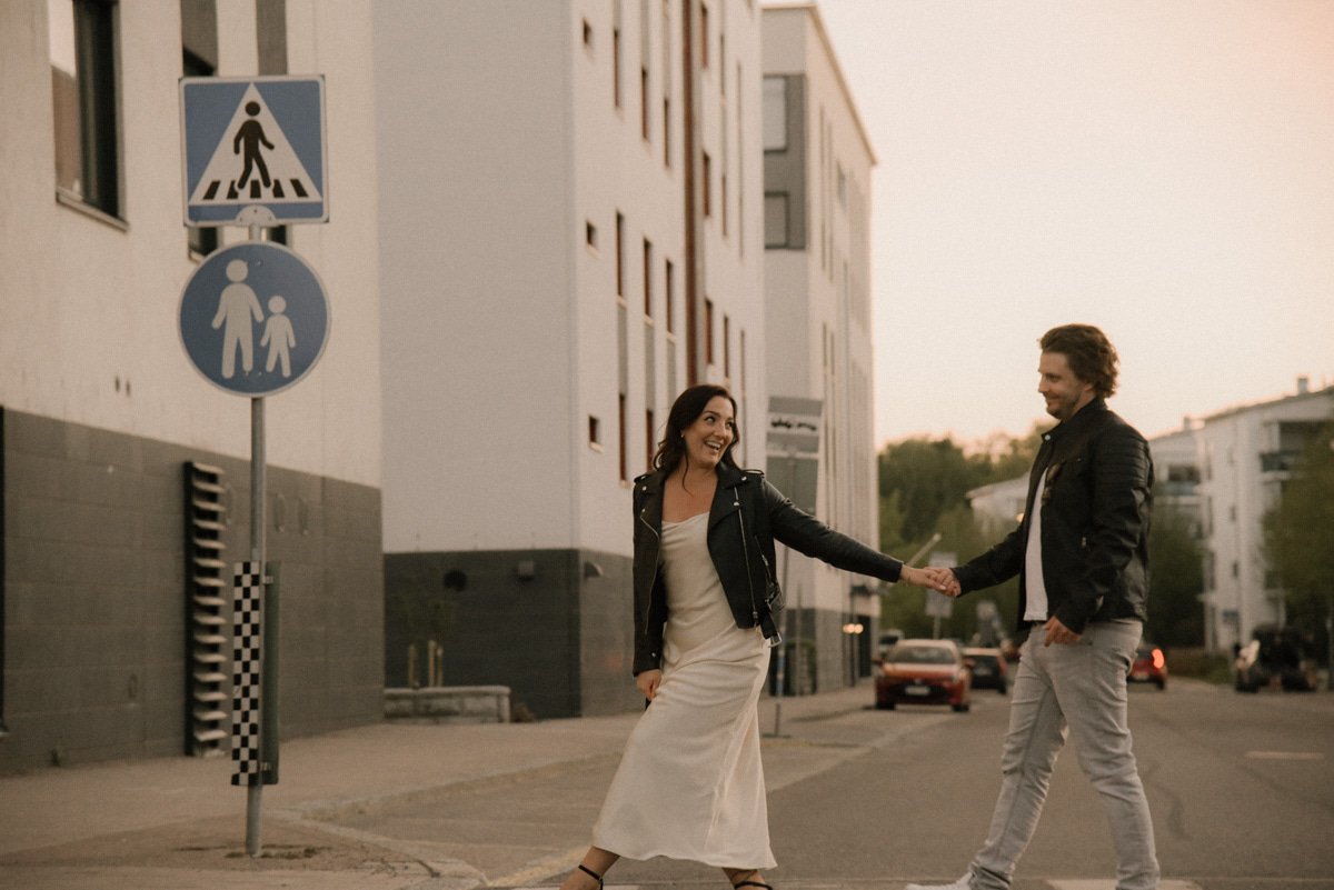 Onnellinen pariskunta ylittää katua kuvassa. Pariskuntakuvaus Vantaa.