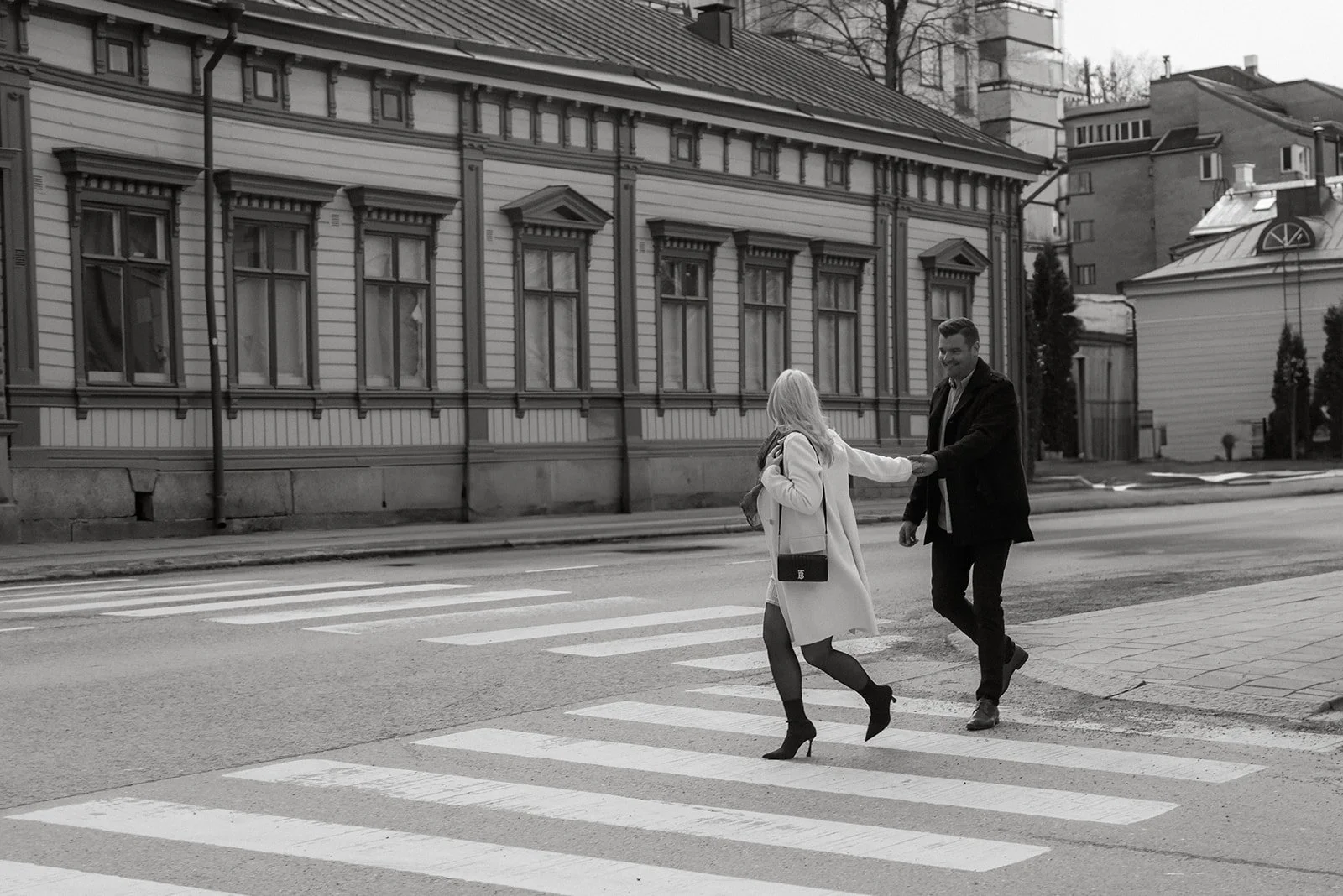 Pariskunta kävelee käsi kädessä kaupunkimaisemassa.