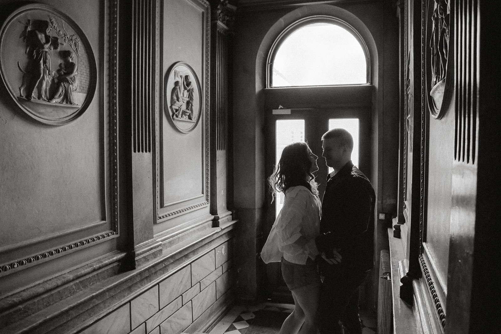 Mustavalkoinen pariskuntakuva, jossa nainen ja mies seisovat lähekkäijn käytävässä.