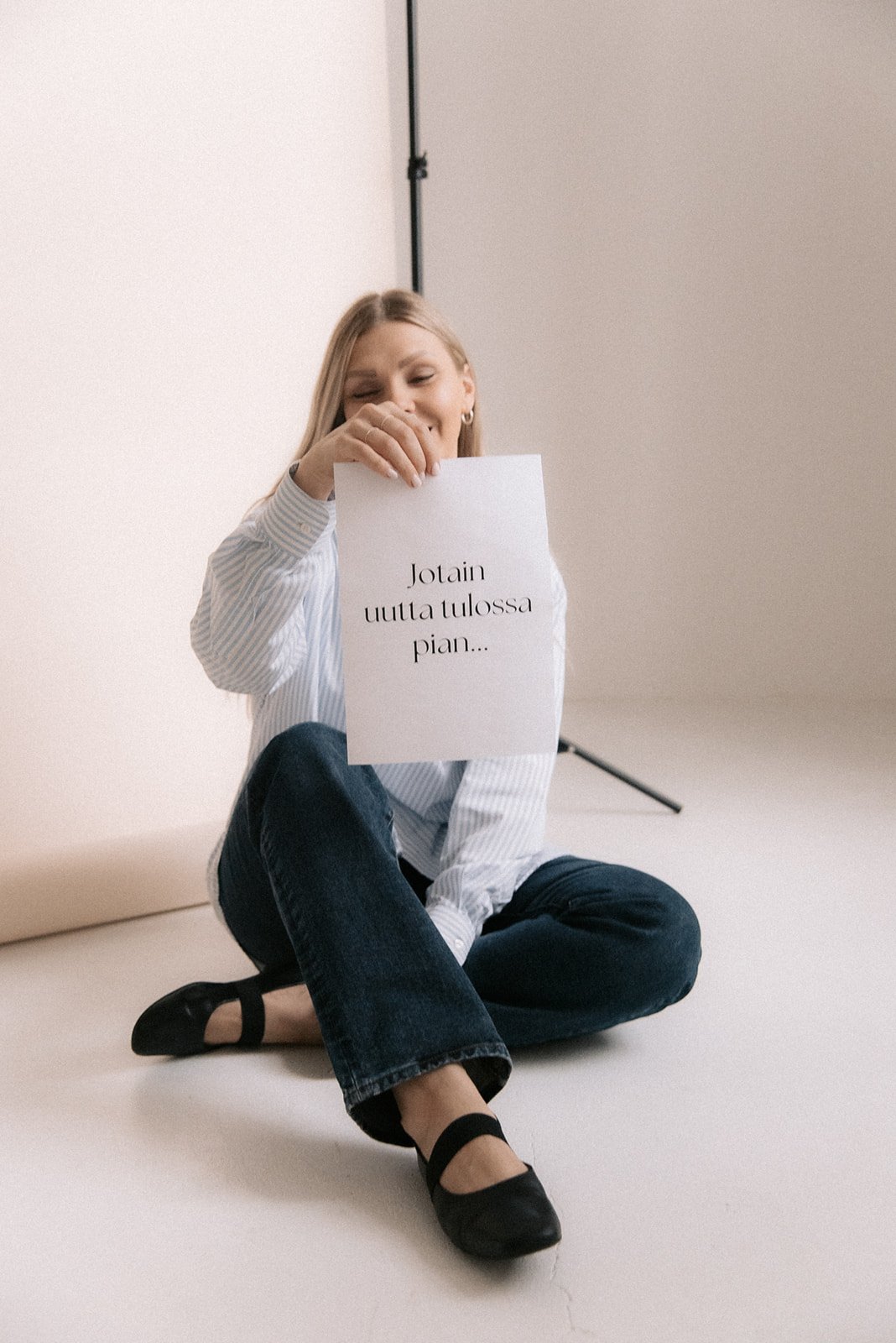 Heartive yrittäjä Terhi Lahti istuu valokuvausstudion lattialla kädessään paperi, jossa lukee "jotain uutta tulossa pian...".