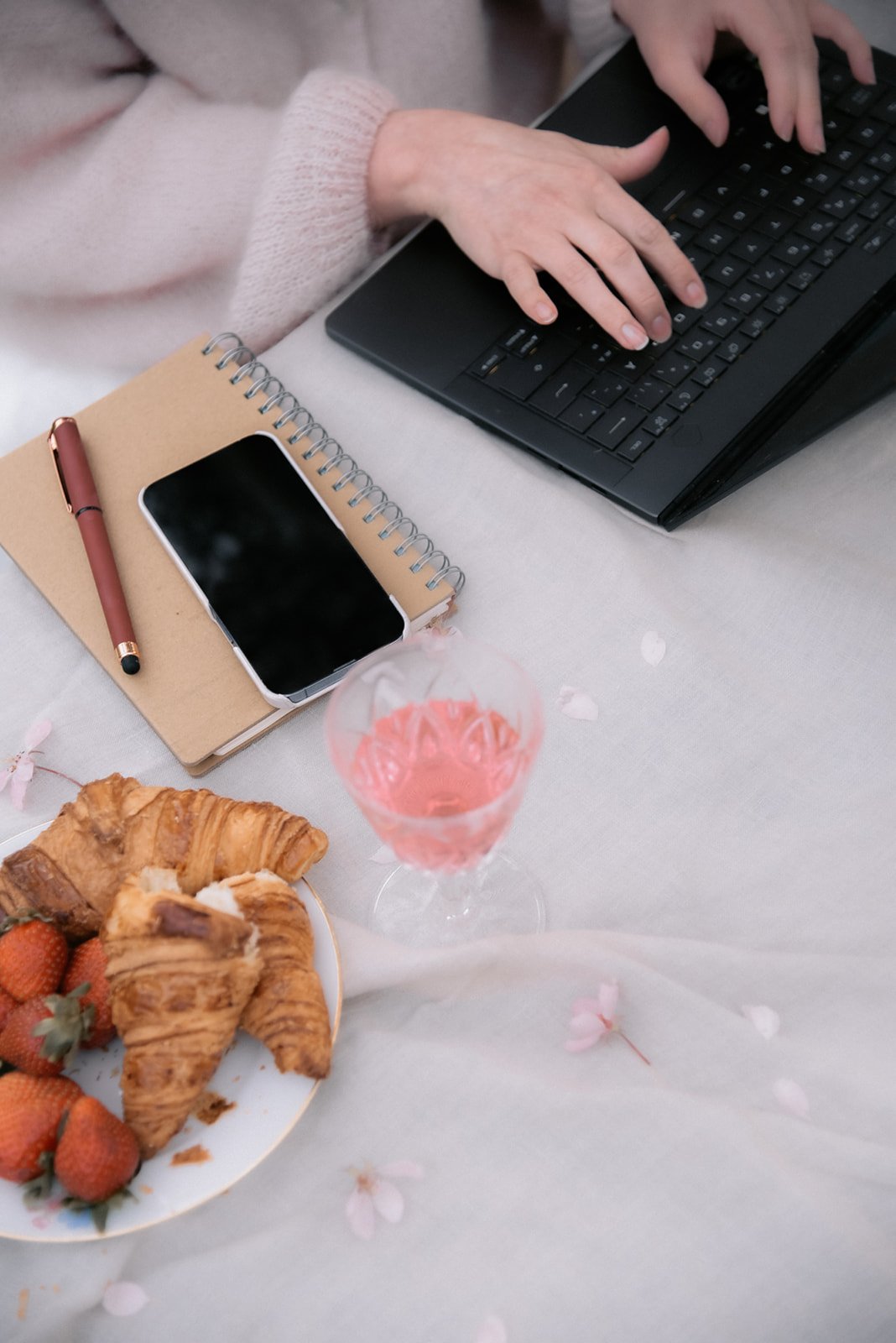 Heidi Väisäsen ottama brändikuva, jossa yrittäjä naputtelee tietokonettaan puhelin ja piknikeväät vieressään.