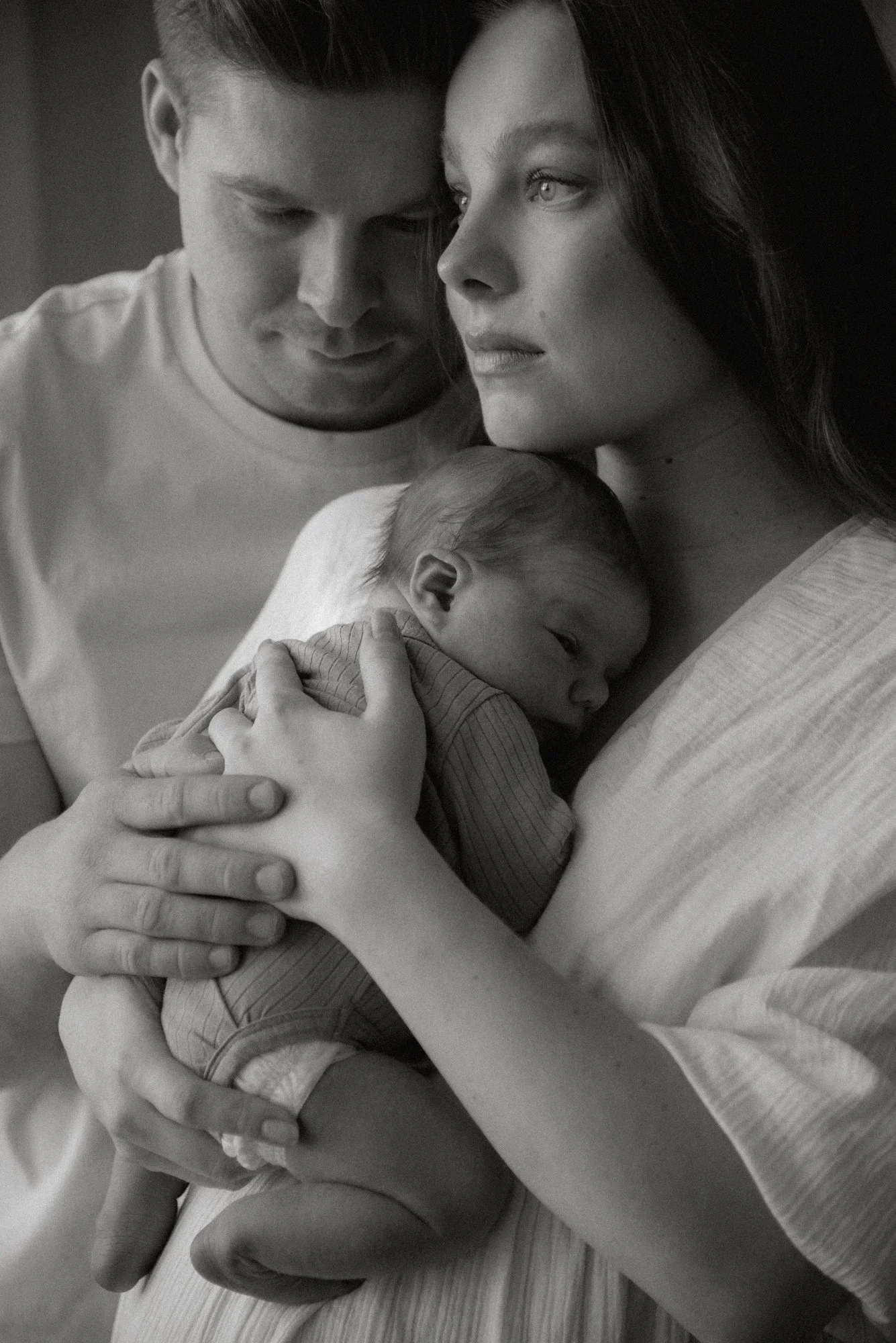 Vastasyntyneen kuvaus. Äiti pitelee vauvaa rinnallaan ja isä tukee kädellä vauvan selästä.