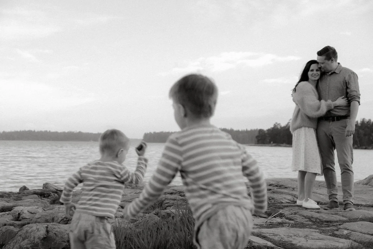 Perhekuvaus Helsinki, vanhemmat halaavat toisiaan, edustalla kaksi juoksevaa lasta.