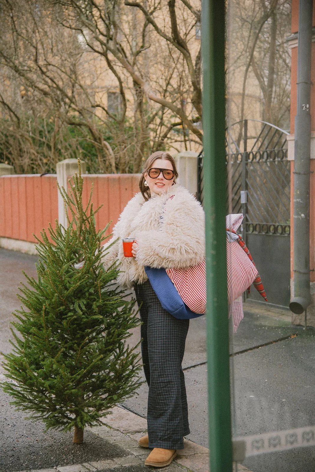 Edlan brändikuvaus kaupunkimaisemassa Helsingissä. Yrittäjä seisoo brändin laukkuja olallaan ja pitelee joulukuusta.