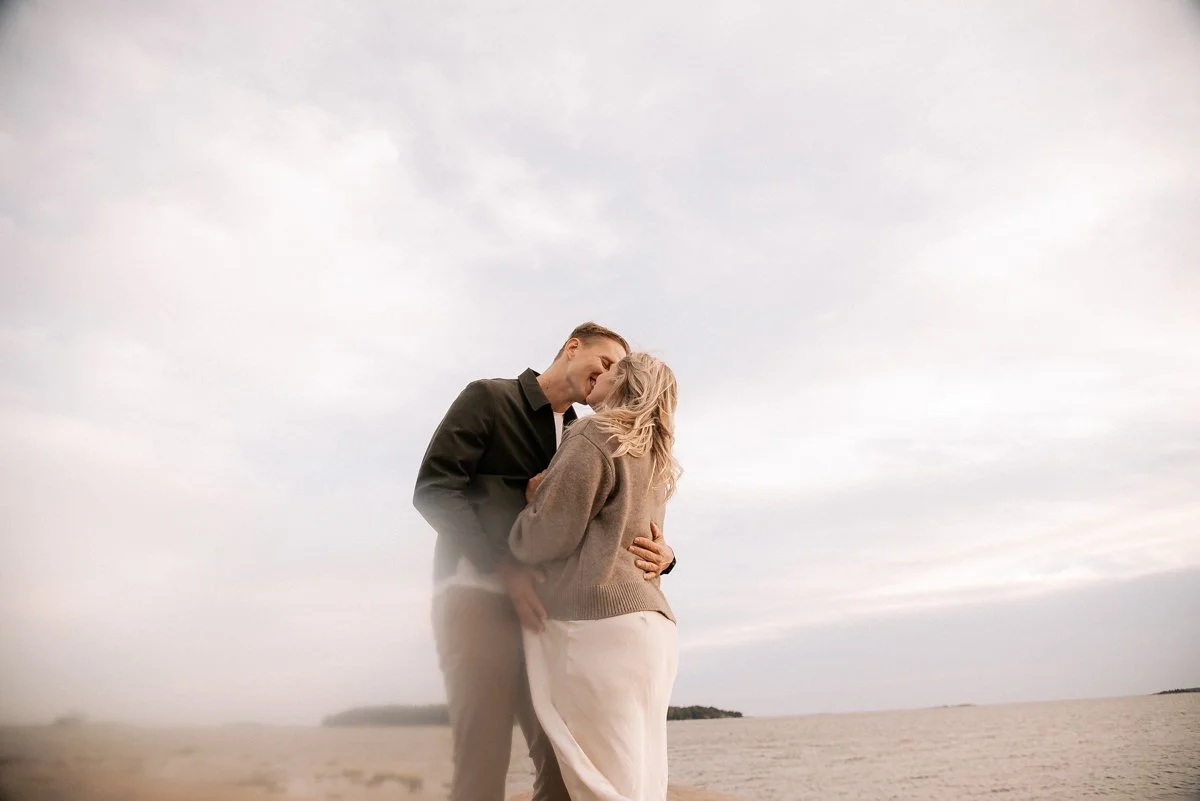 Suuteleva pariskunta rannalla. Odotusajankuvaus Helsinki.