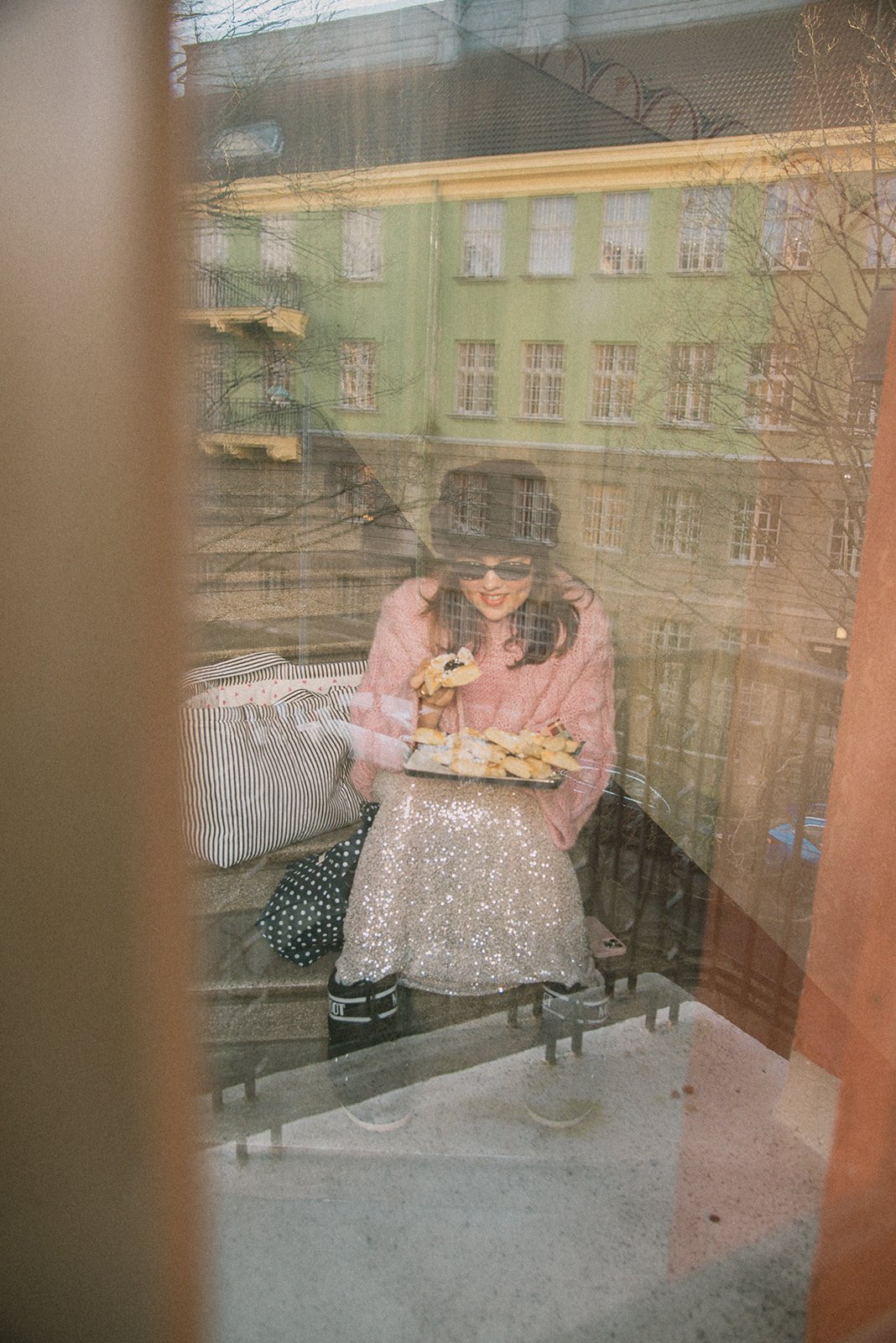 Edlan yrittäjä istumassa rappukäytävässä ja syömässä joulutorttuja. Kuva on kuvattu ikkunan läpi.