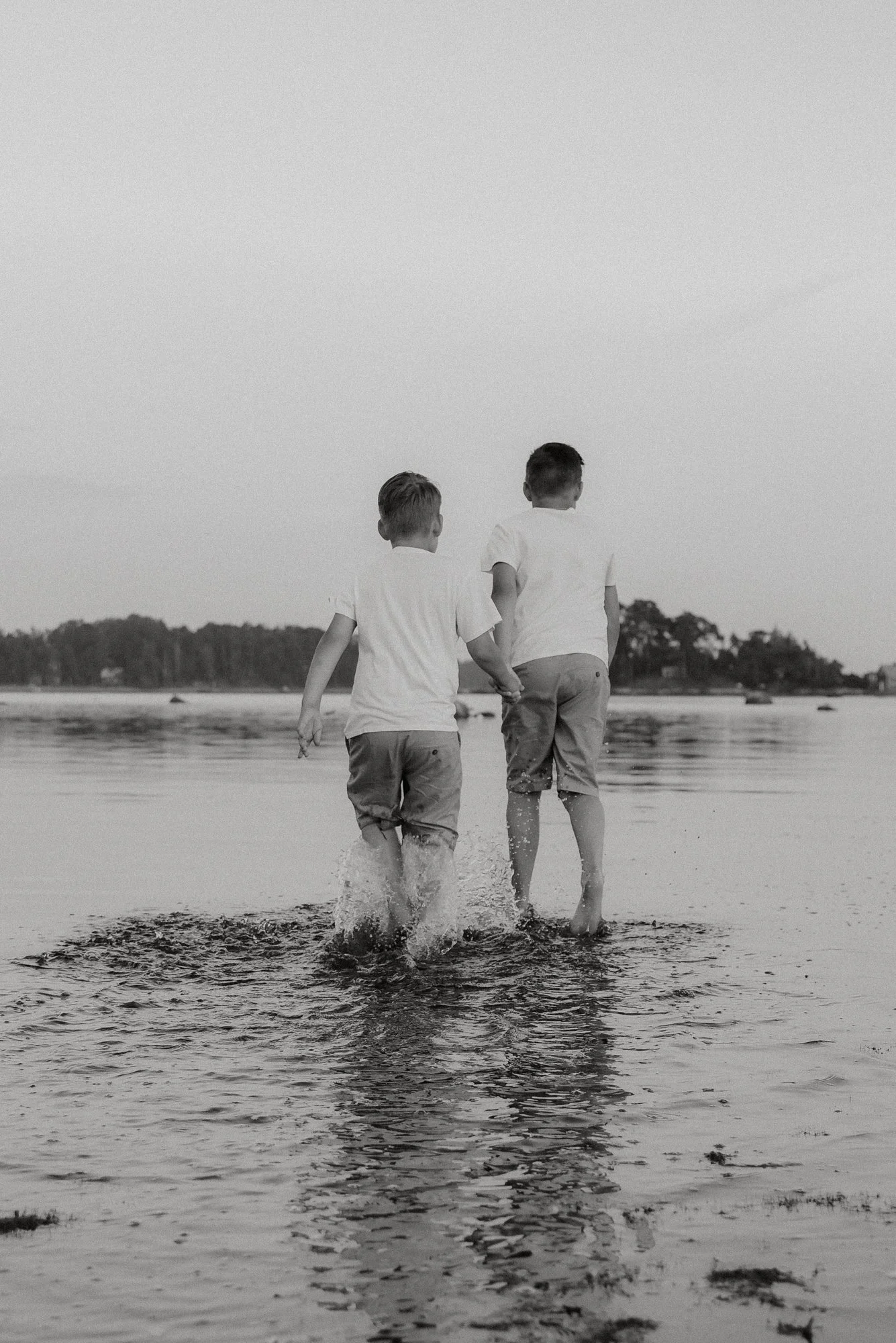 Perhekuvaus Espoo, kaksi lasta kahlaa vedessä.