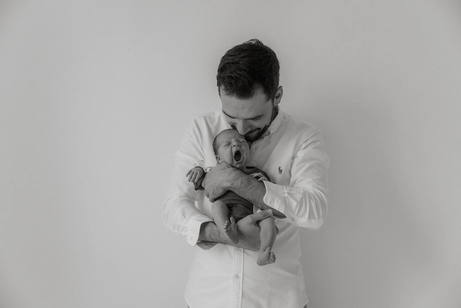 Mustavalkoisessa kuvassa vastasyntynyt vauva isän sylissä.