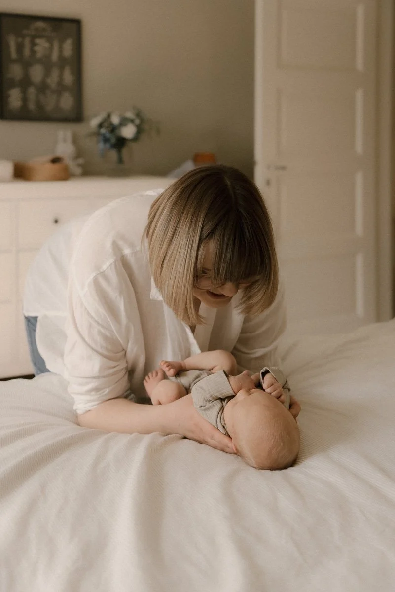 Äiti pitelee lastaan hellästi käsiensä välissä. Vauvakuvaus Espoo.