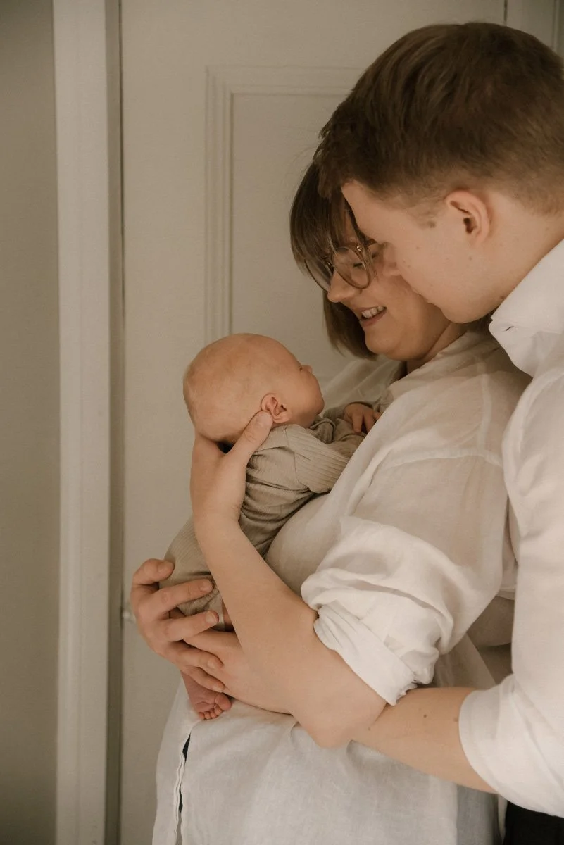 Seesteinen perhekuva, äiti, isä ja vauva omassa kodissaan.