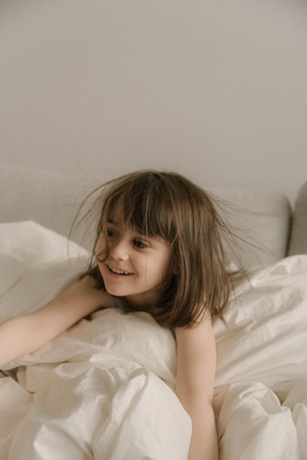 Leikkivä tyttö vaaleassa kuvassa. Lapsikuvaus kotona.