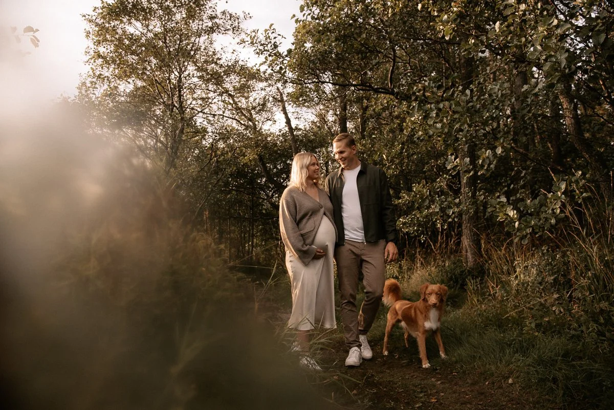 Perhe vehreissä maisemissa koiransa kanssa. Raskausajan kuvaus Helsinki.