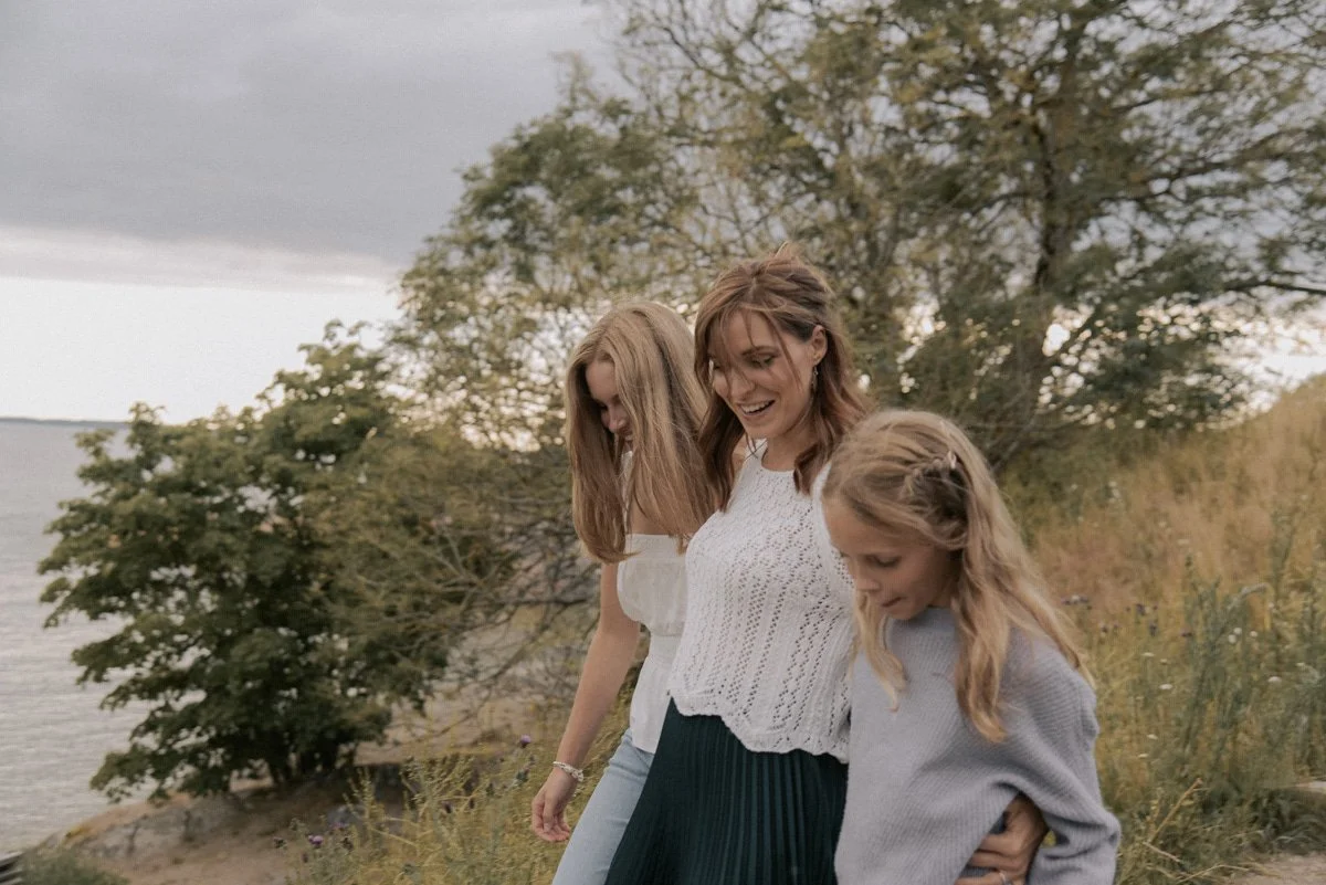 Perhekuvaus miljöössä, äiti ja kaksi lasta kahlaa kävelevät vierekkäin. Kuvannut valokuvaaja Heidi Väisänen.