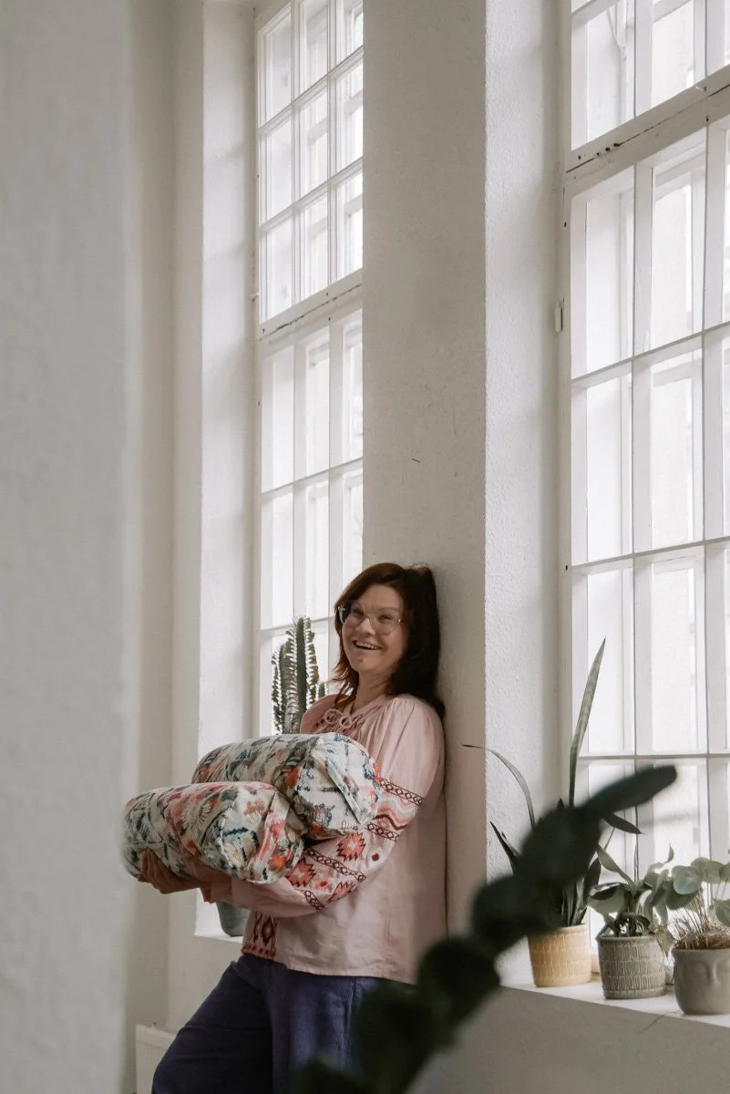 Verhoomoyrittäjä Virve pitelee käsissään värikkäitä tyynyjä. Kuvannut henkilökuvaaja Heidi Väisänen.