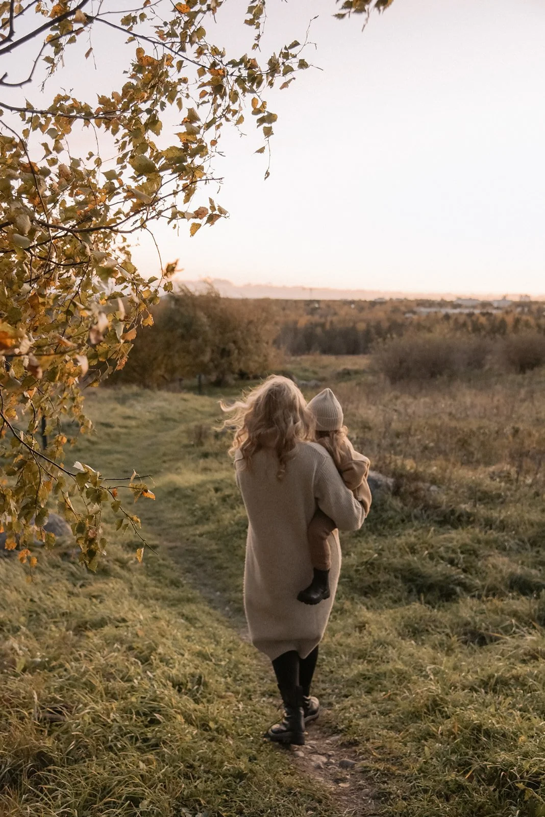 Perhekuvaus Espoo, äiti kävelee lapsi sylissään luonnossa.