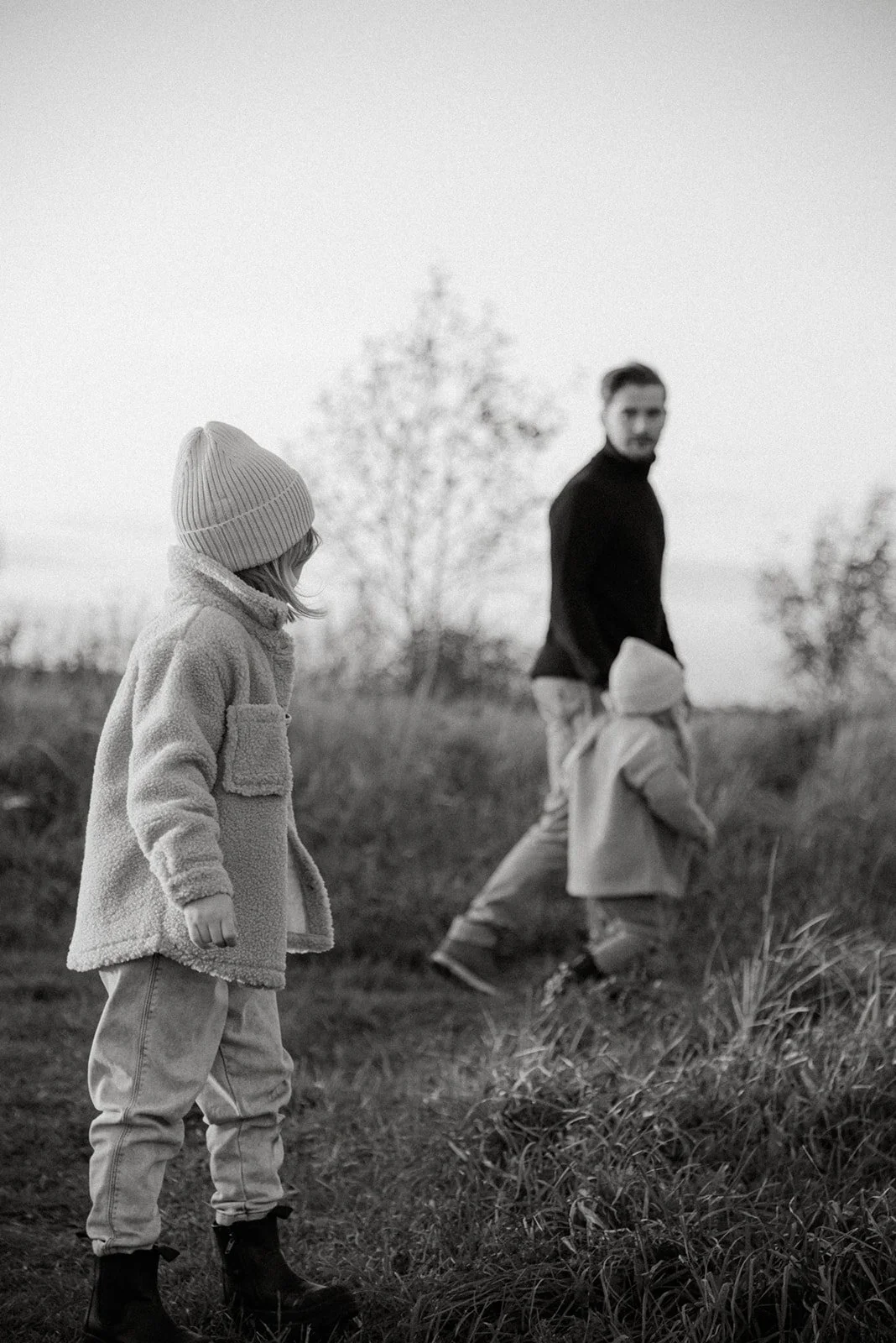 Mustavalkoinen perhekuva. Isä ja kaksi lasta.