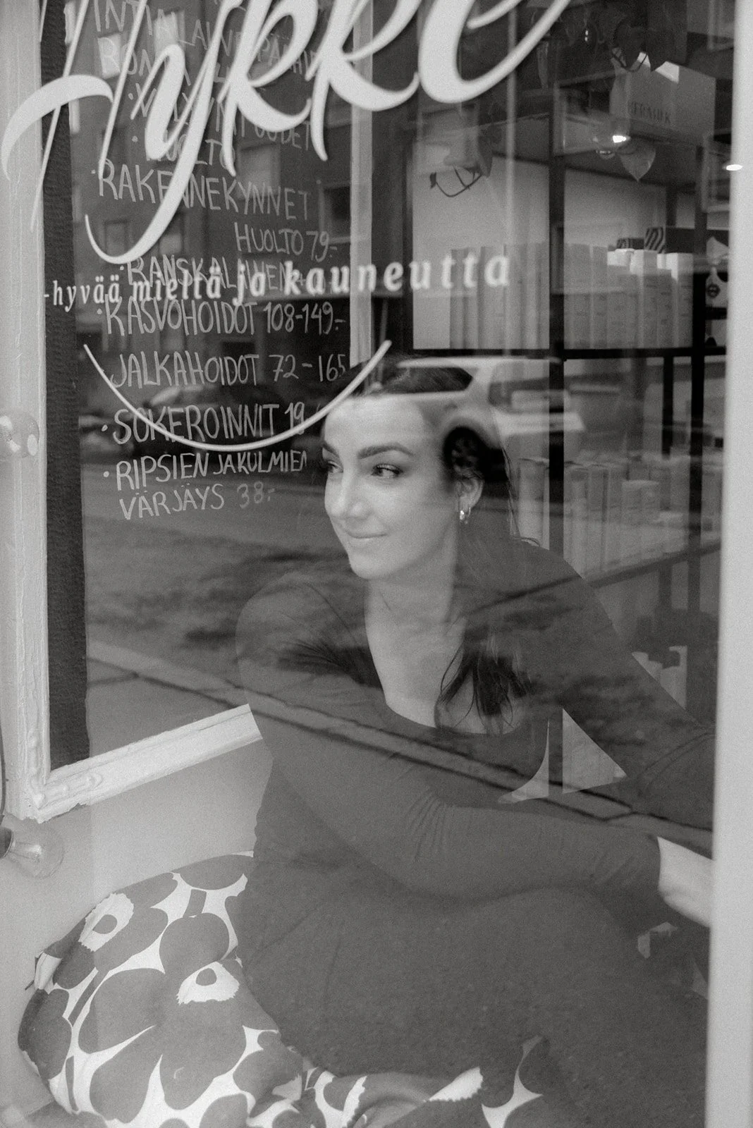 Kampaaja katsoo liiketilan ikkunasta ulos mustavalkoisessa kuvassa. Kuvannut yrityskuvaaja Heidi Väisänen.