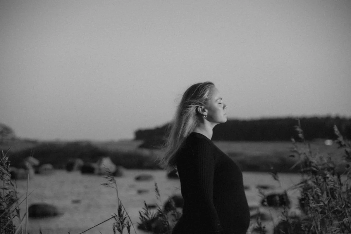 Mustavalkokuva, jossa raskaana oleva nainen kasvot kääntyneenä valoa kohti.