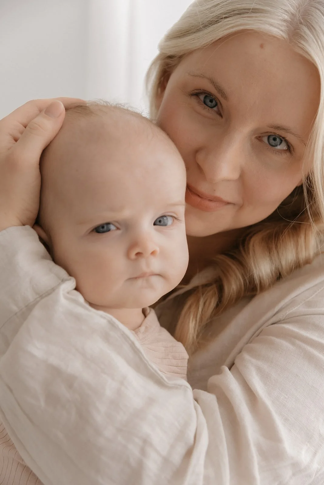 Äiti pitää pientä lastaan sylissä valoisalla studiolla Keravalla, äiti- ja lapsikuvaus.