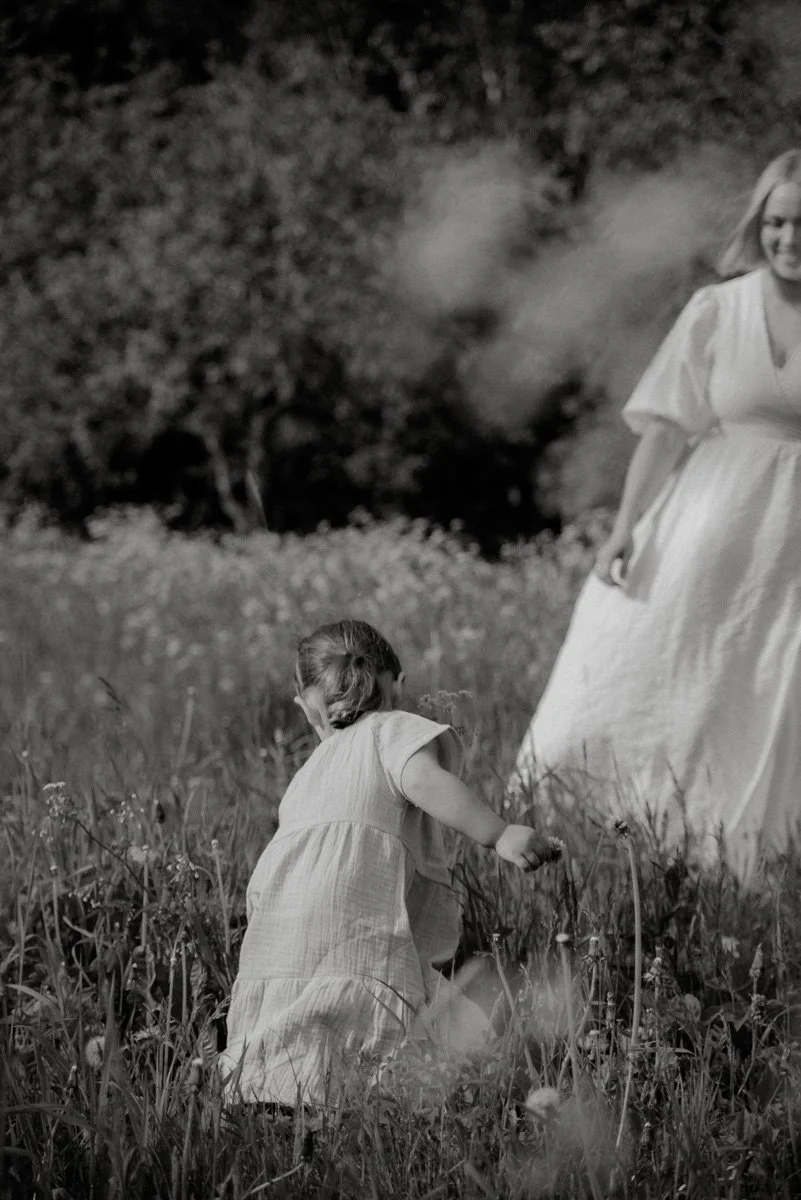 Äiti ja lapsi kirmaavat kauniilla niityllä.