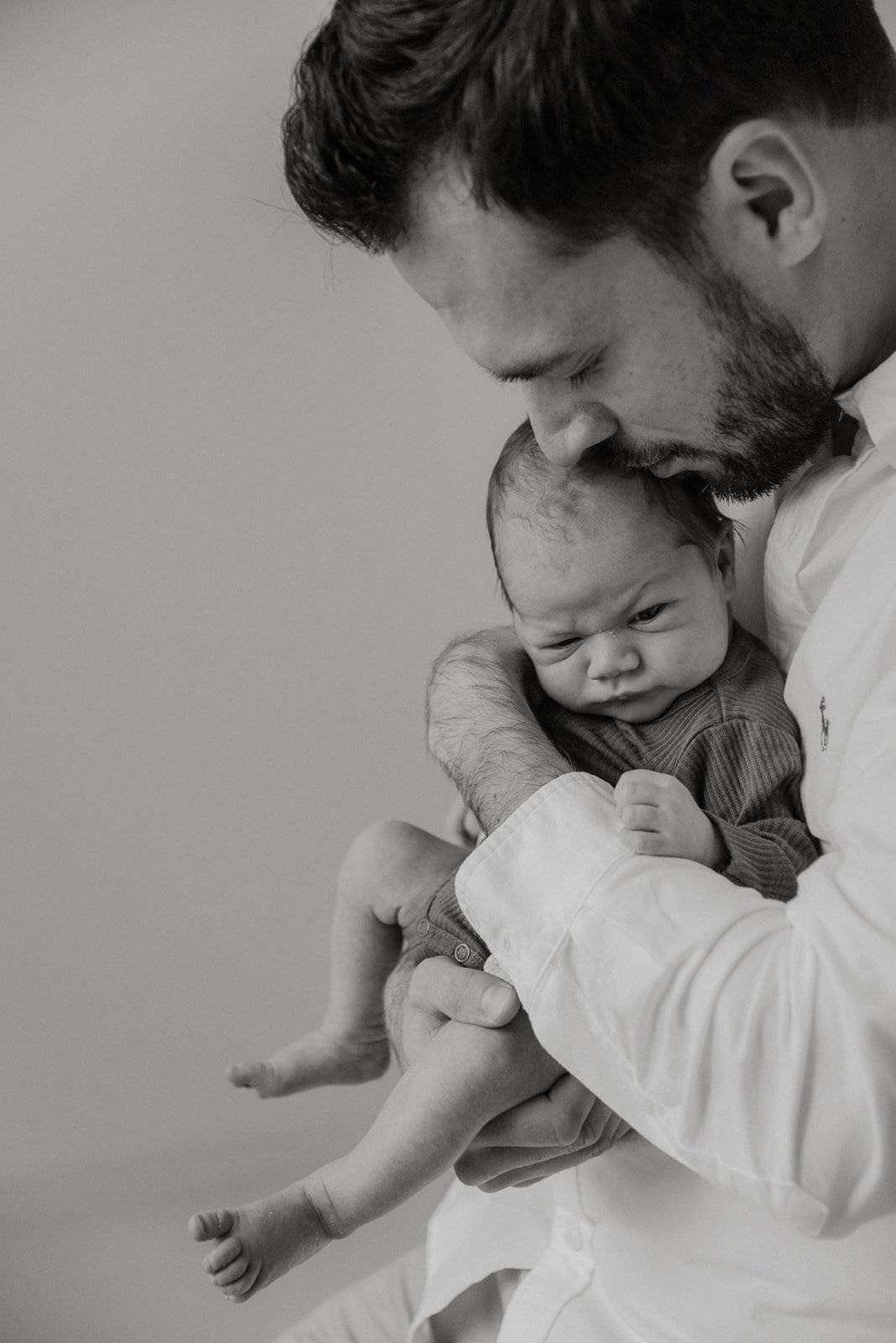 Vastasyntynyt vauva isän syleilyssä. Vauvakuvaus Heidi Väisänen studiolla Keravan Saviossa.