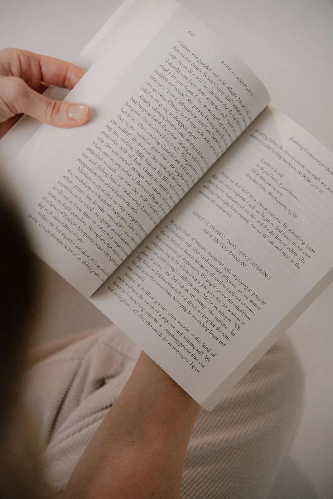 Kuva avonaisesta kirjasta naisen käsissä.