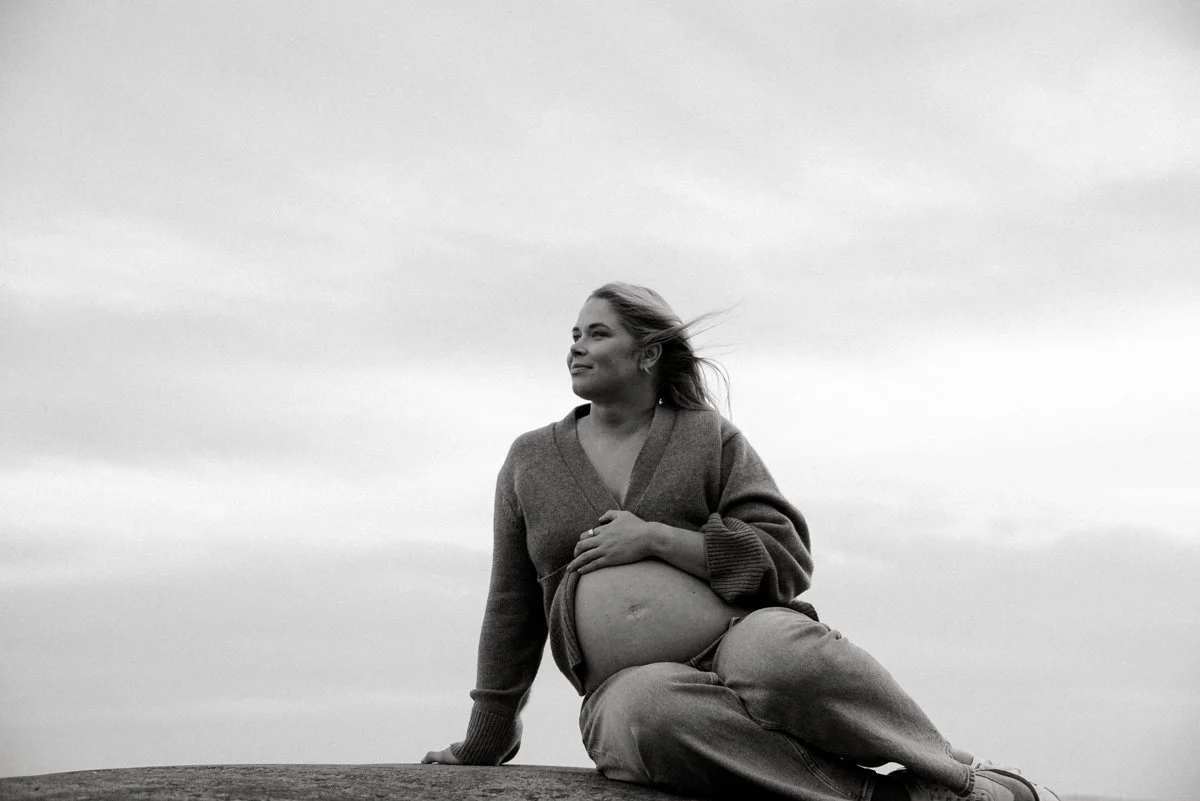 Raskaana oleva nainen pitelee vatsaansa mustavalkoisesa kuvassa. Odotusajankuvaus Espoo.