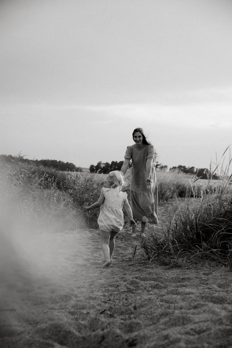 Perhekuvaus Helsinki, äiti ja lapsi juoksevat rantahiekalla. Kuvannut valokuvaaja Heidi Väisänen.