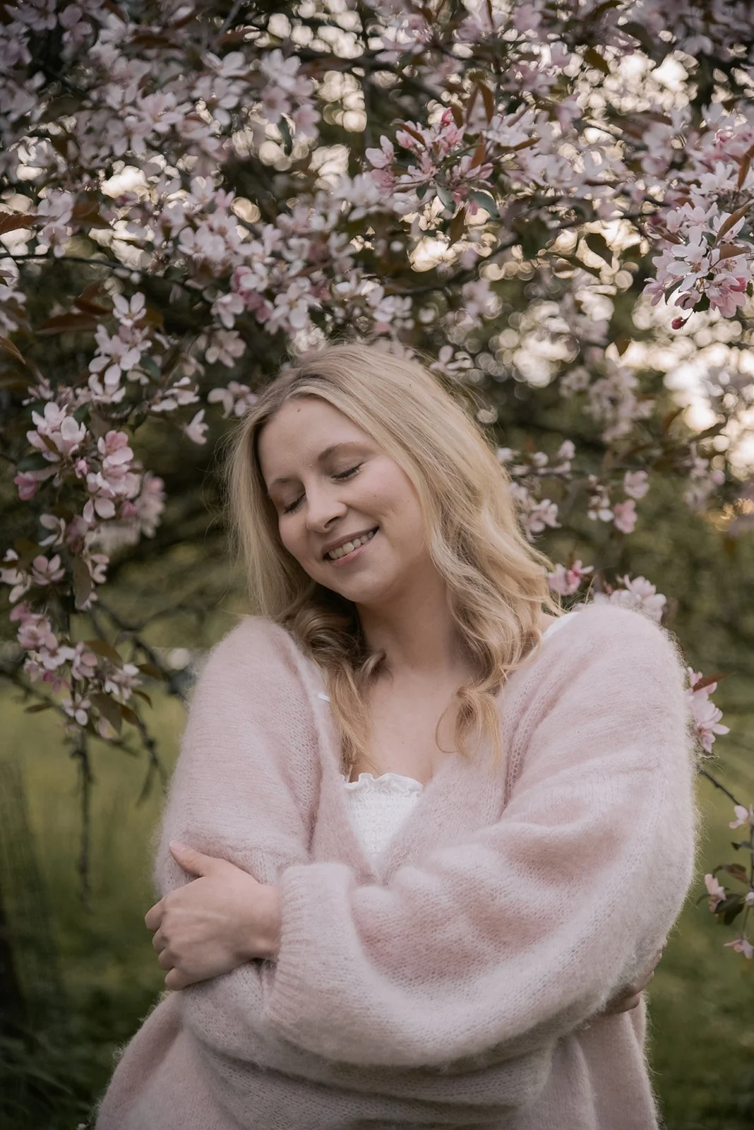 Henkilökuva doula Jutta Alasesta kirsikkapuun edessä.