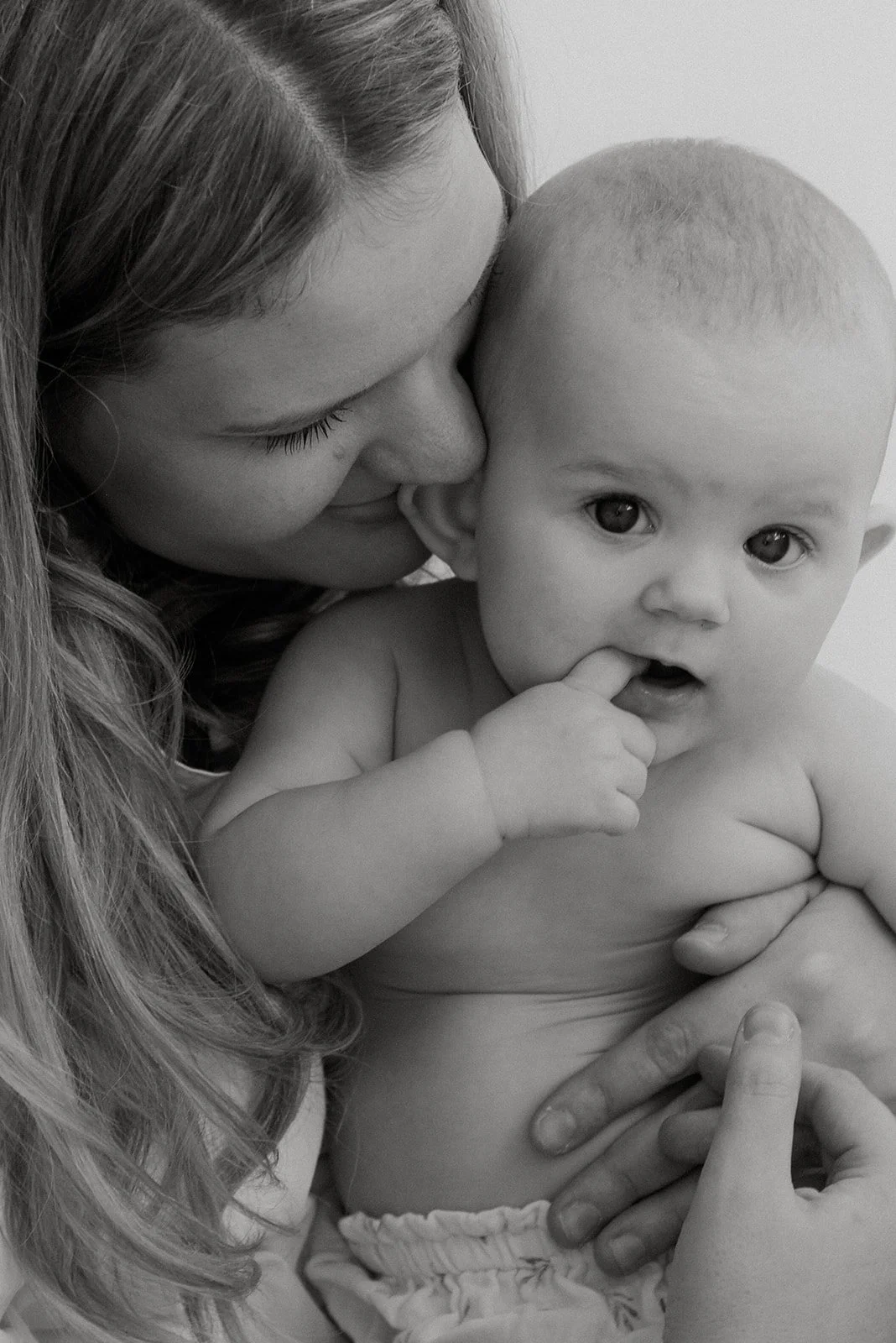 Äidin lämmin ja hellä kosketus, vauva sylissä. Äiti- ja lapsikuvaus Heidi Väisäsen studiossa Uudellamaalla.