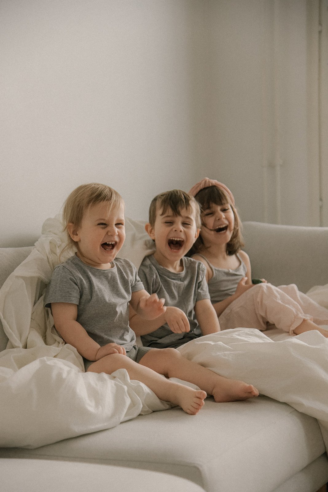 Nauravaiset lapset sohvalla. Sisarkuvaus kotona.