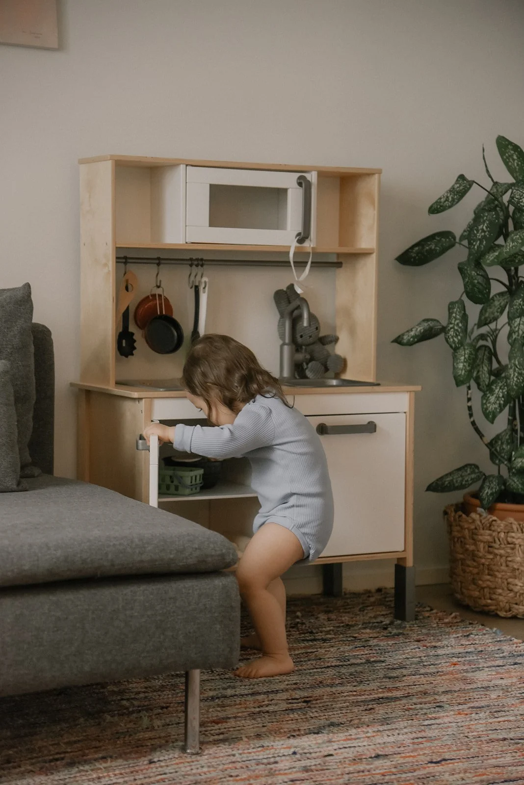 Lapsi leikkii lelukeittiöllä olohuoneessa. Lapsikuvaus kotona.