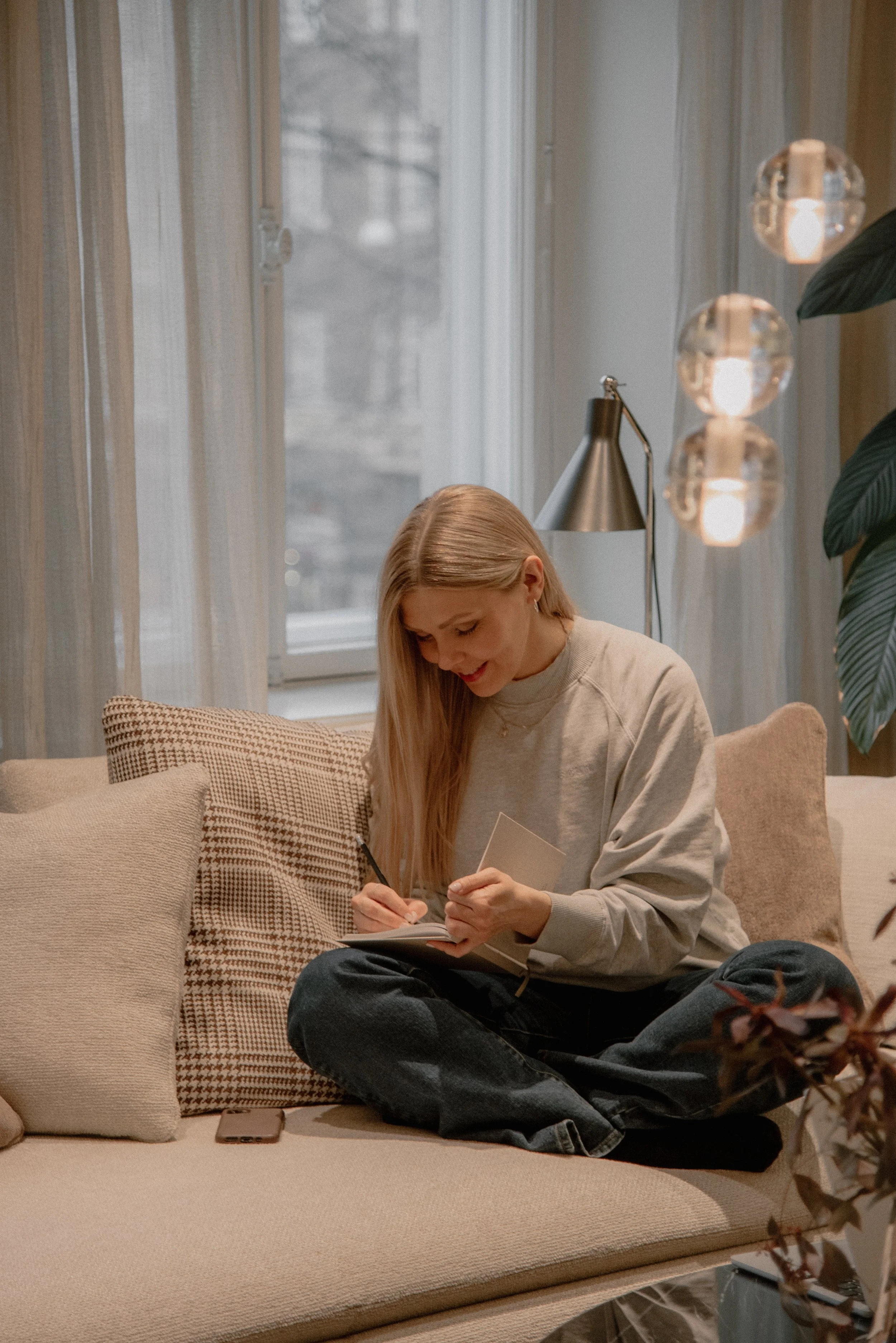 Yrittäjä tekee muistiinpanoja muistivihkoon valoisassa olohuoneessa.