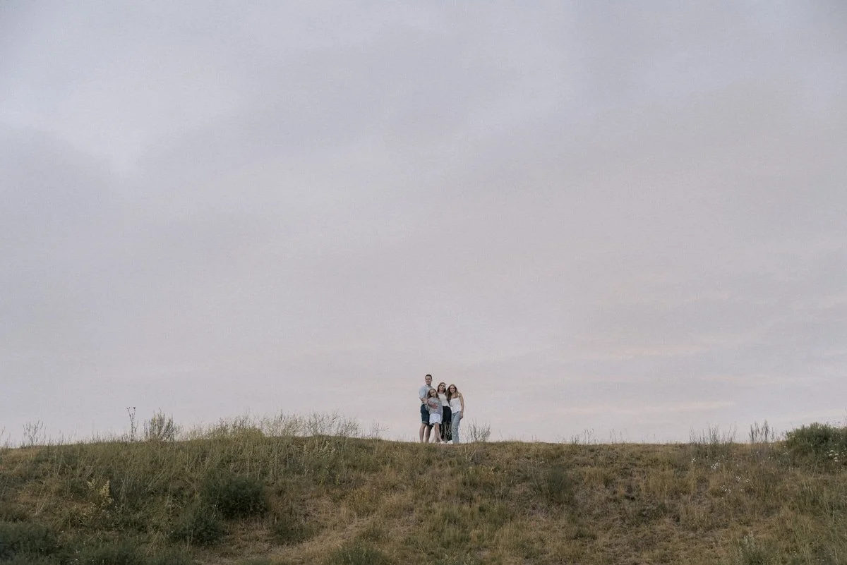 Perhe kaukaa kuvattuna luontomaisemassa.