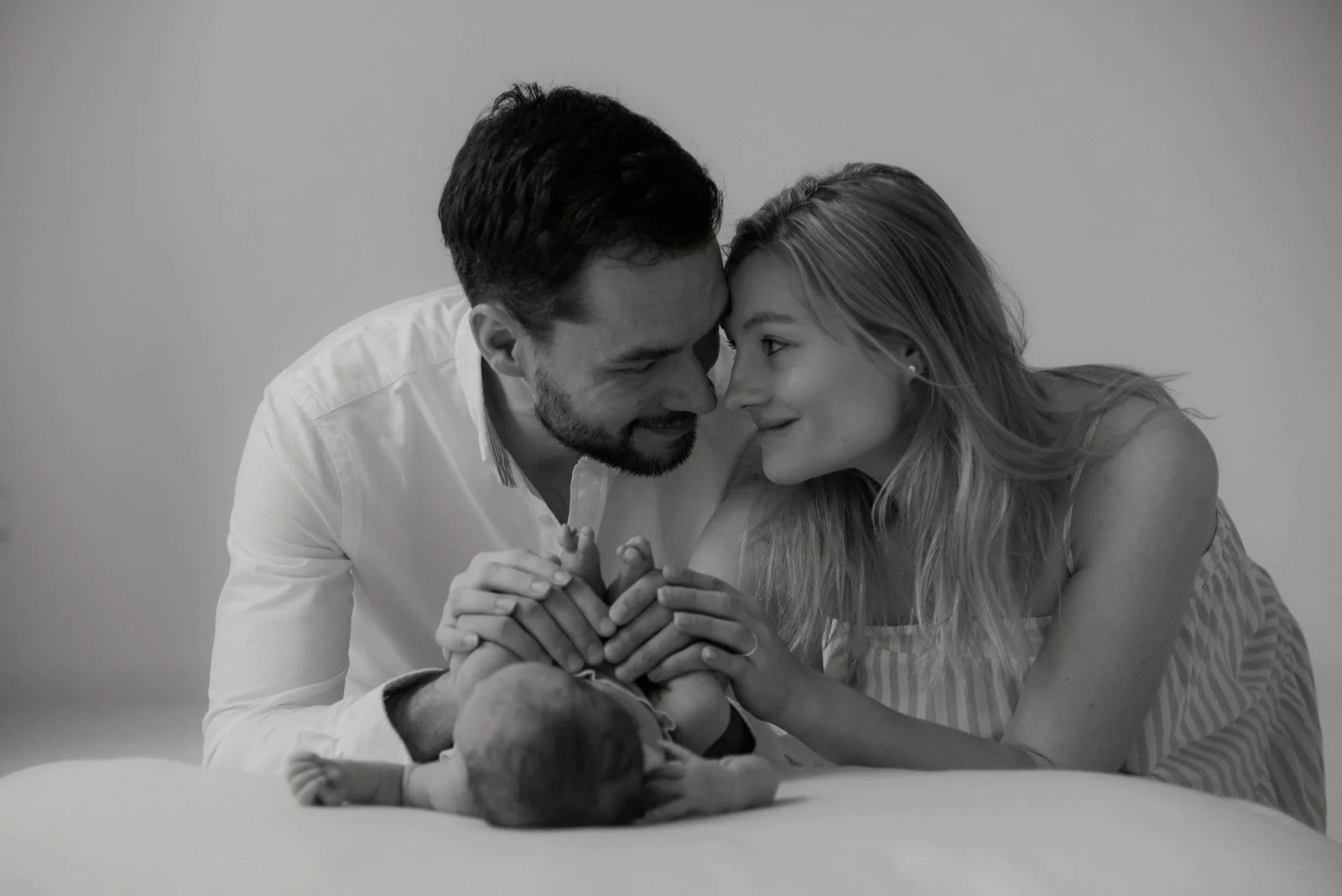 Nukkuva vauva ja toisiaan katsovat vanhemmat. Vastasyntyneen kuvaus valokuvaaja Heidi Väisäsen studiolla Keravan Saviossa.