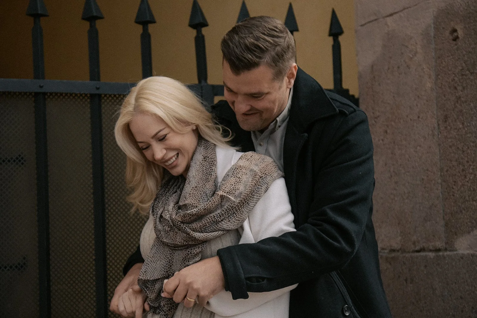 Onnellinen pariskunta halaa toisiaan porttikongin edessä kaupunkimaisemassa. Pariskuntakuvaus Helsinki.