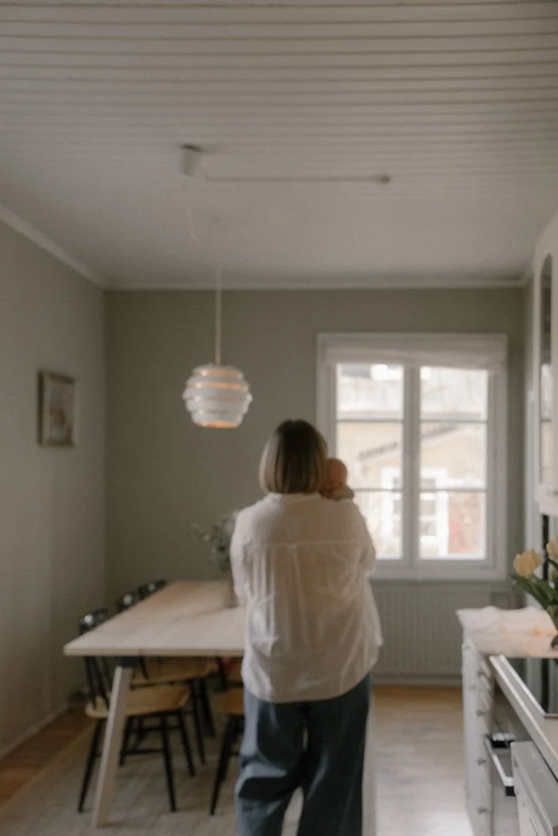 Äiti kävelee kotonaan vauva sylissään. Perhekuvaus Vantaa.