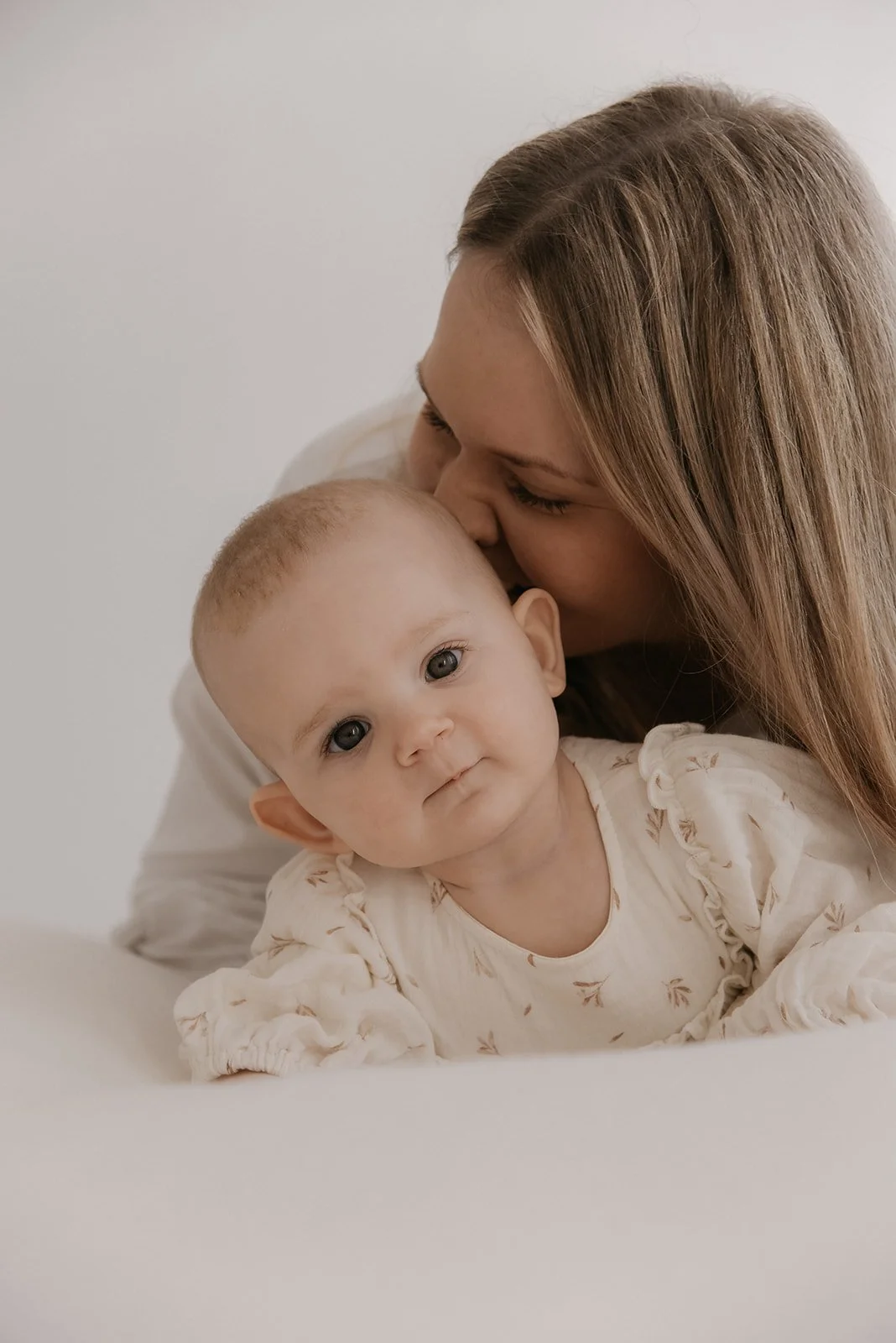 Äiti- ja lapsikuvaus, äiti suukottaa vauvaa päähän.