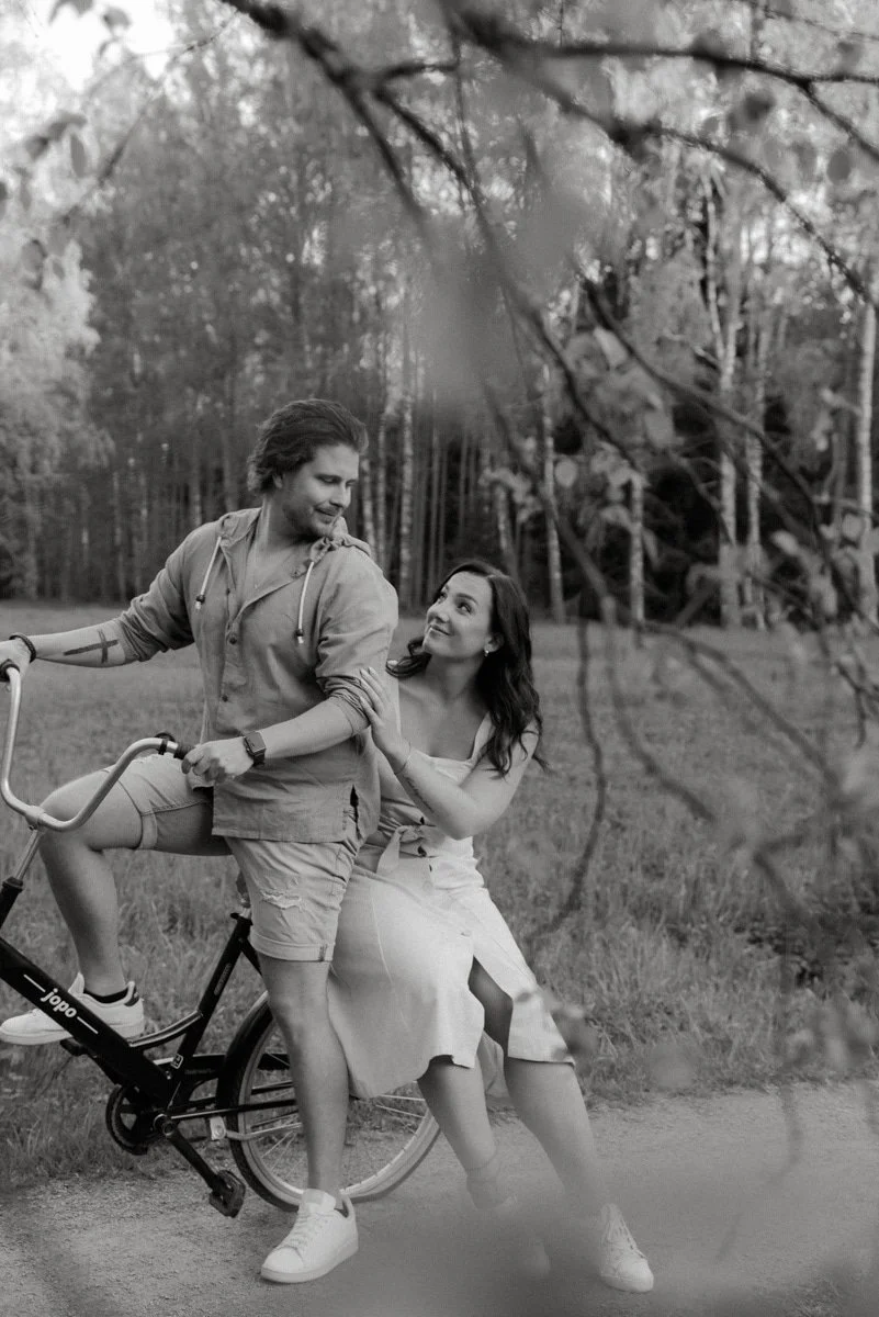 Pariskuntakuvauksessa pariskunta ja pyörä miljöössä.