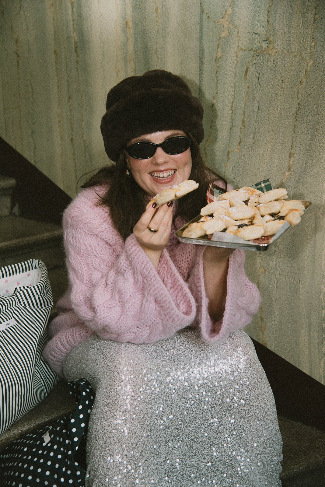 Edlan brändikuvaukset, yrittäjä istuu portailla ja syö hymyillen joulutorttuja.