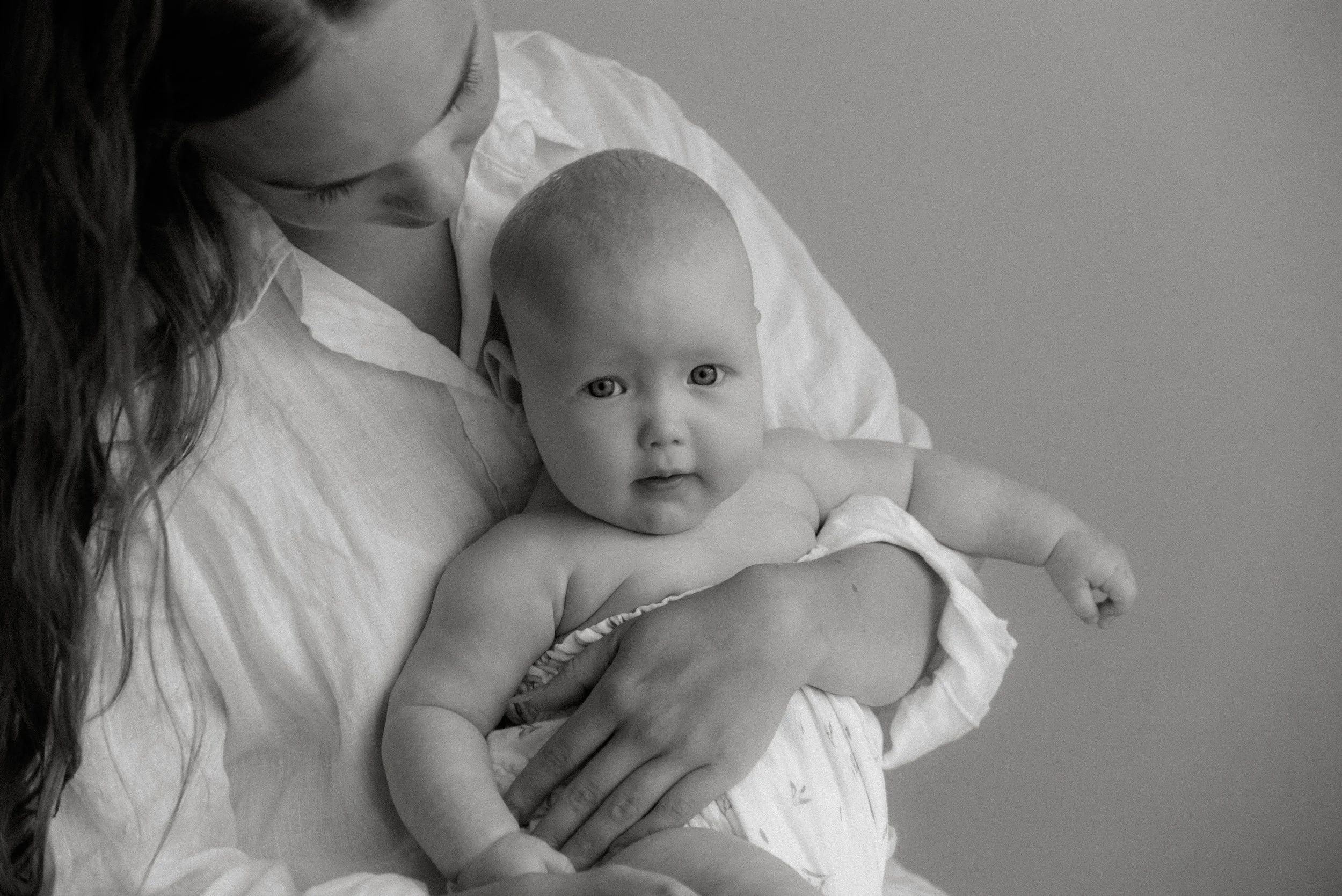 Vauva äidin hellässä syleilyssä. Äiti-lapsivalokuvaus studiossa.