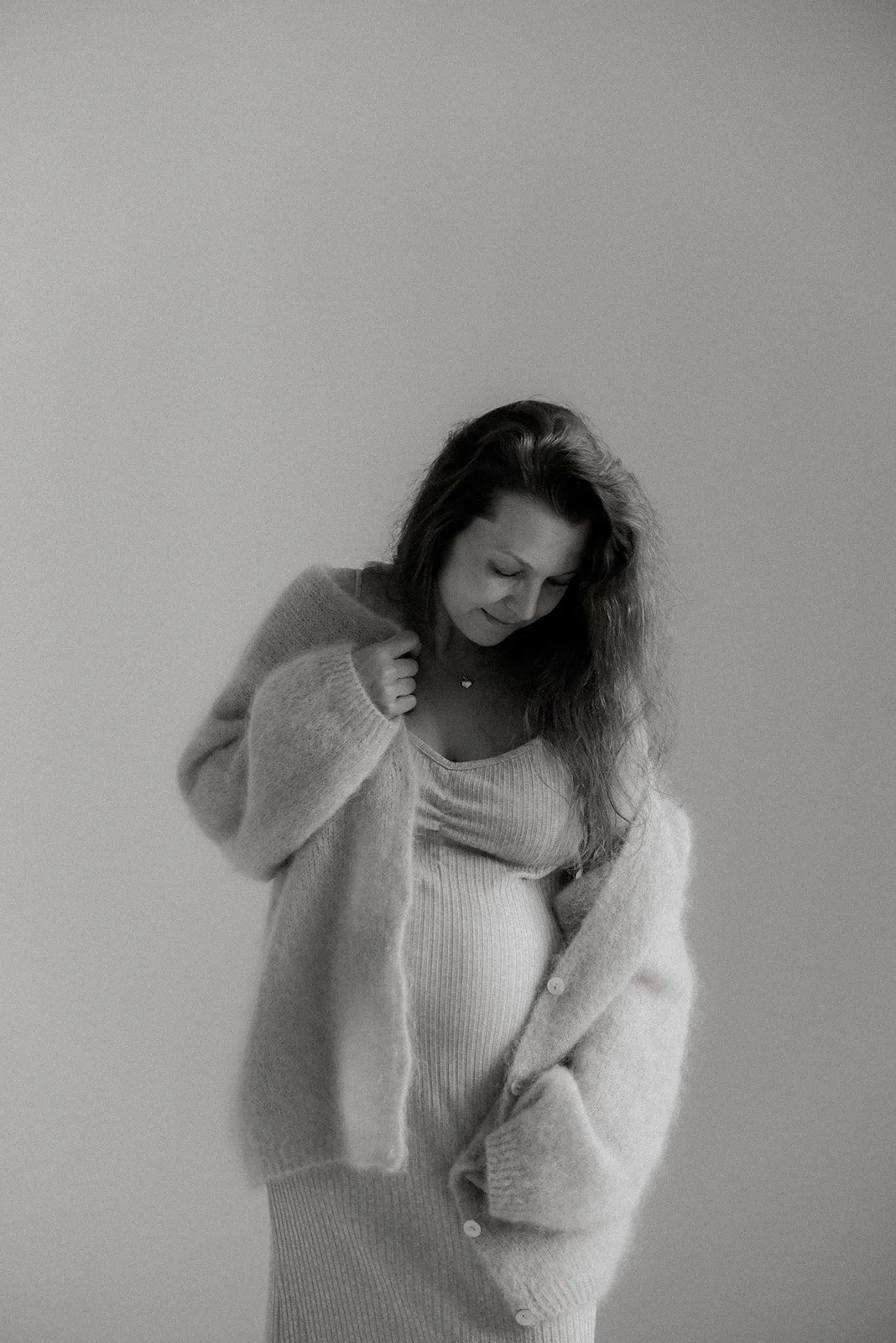 Odottava äiti yllään pehmoinen neule. Kuvan on ottanut raskausajankuvaaja Heidi Väisänen.