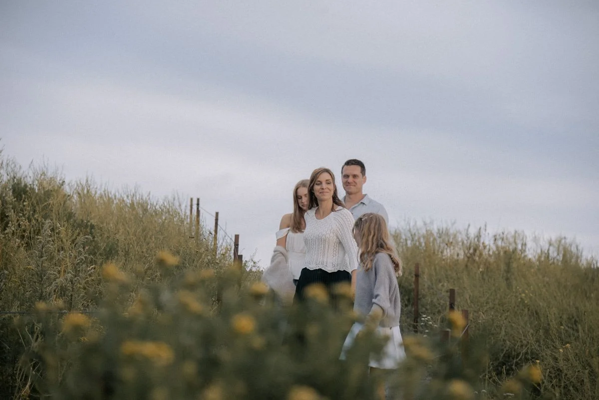 Ulkona otettu perhekuva, vanhemmat ja kaksi lasta seisovat vehreässä maisemassa. Kuvannut Heidi Väisänen.