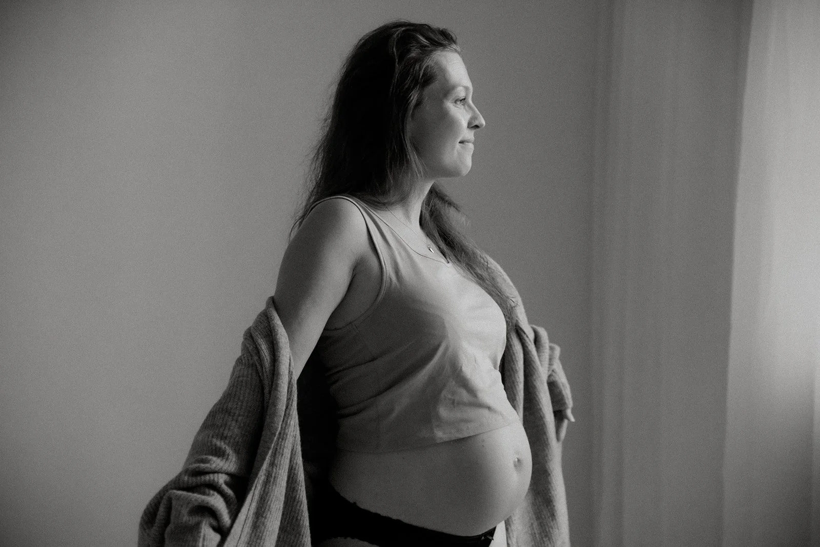 Hymyilevä odottava äiti mustavalkoisessa kuvassa. Kuvan on ottanut raskausajankuvaaja Heidi Väisänen.