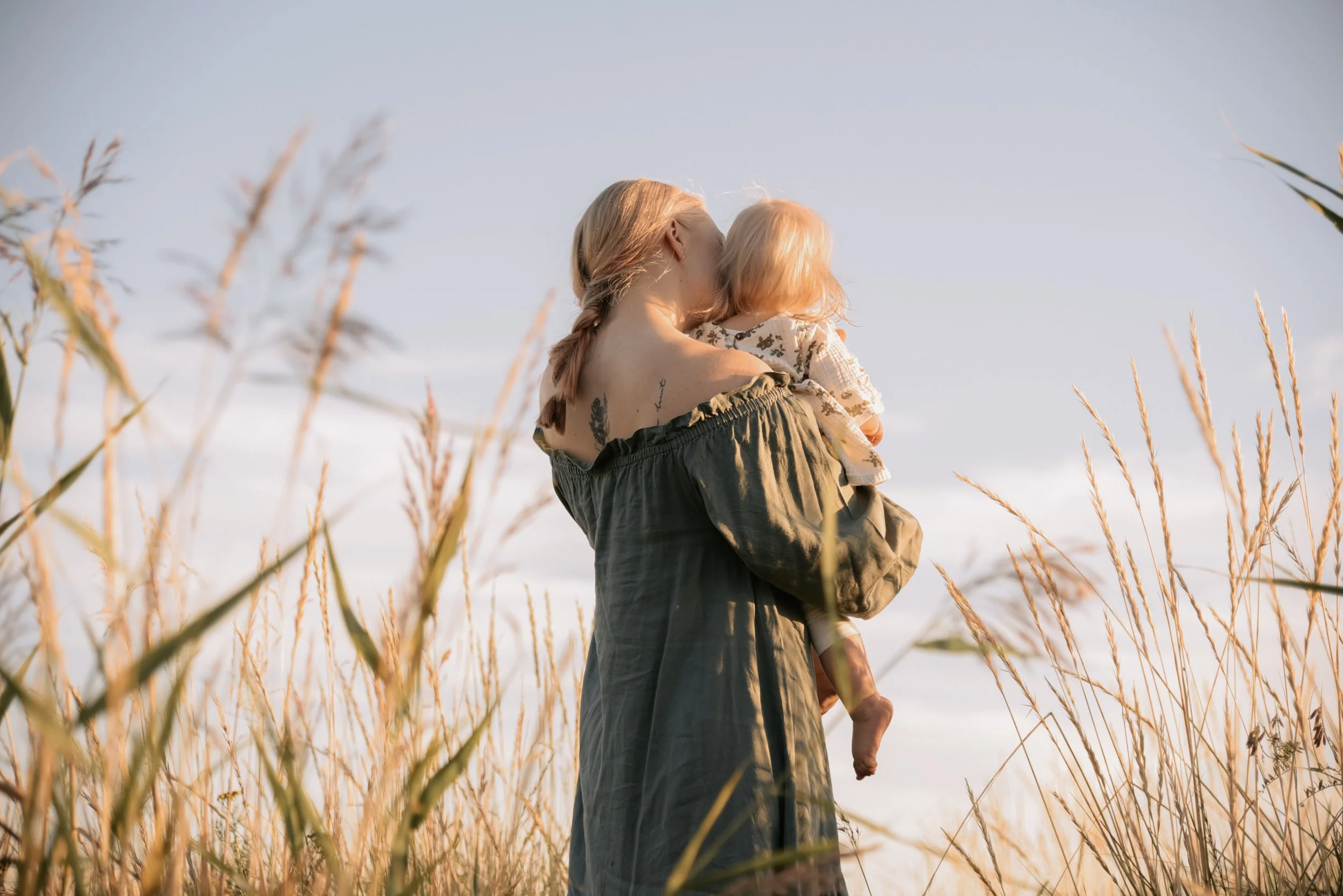 Perhekuvaus Helsinki, äiti heinikossa lapsi sylissään.