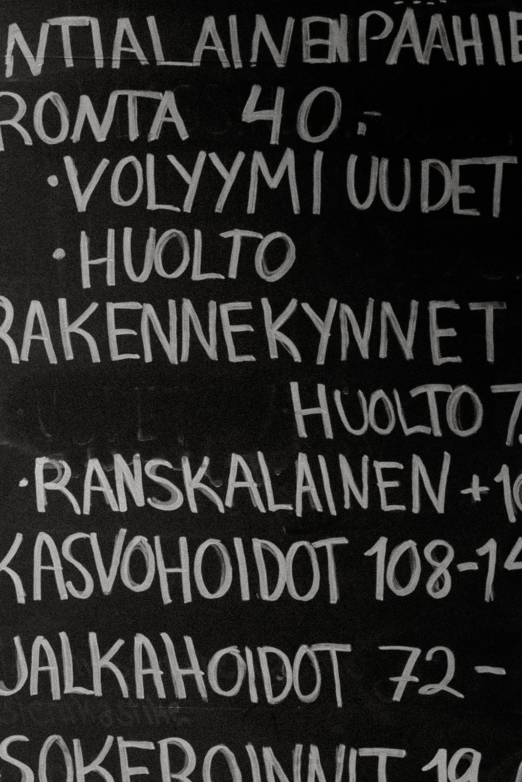 Hykken yrityskuvaus, kampaamon hinnasto kirjoitettuna liitutaululle.