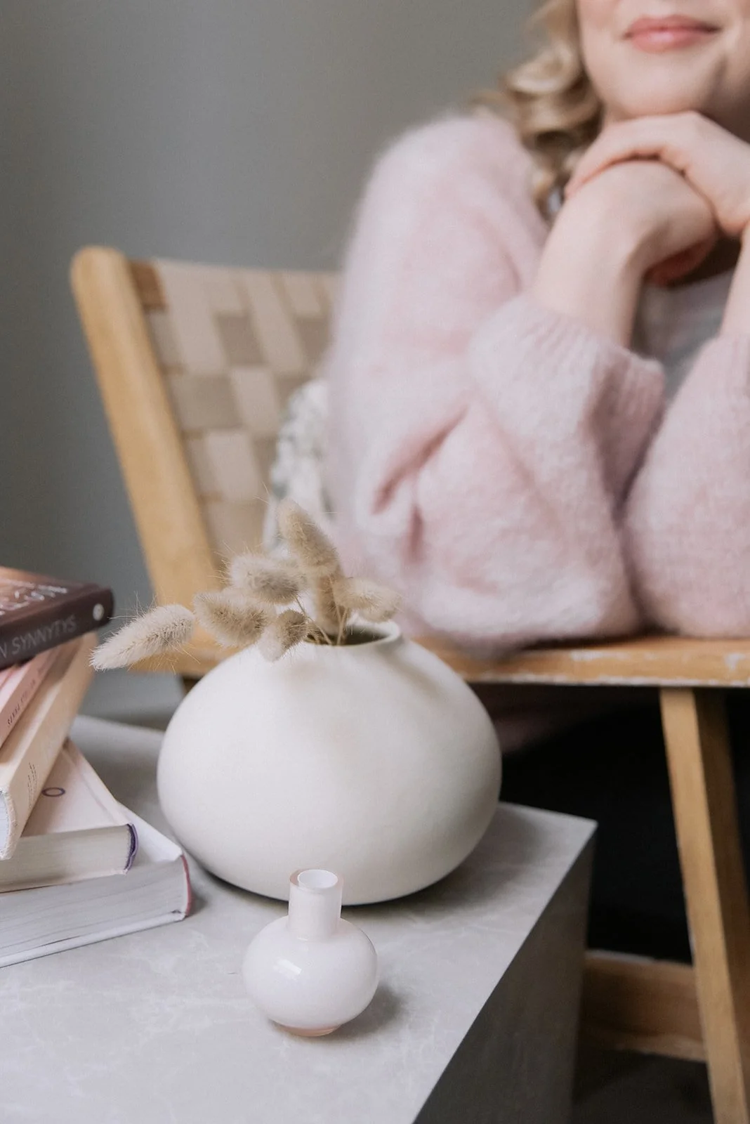 Yrityskuvaus rauhallisessa tilassa, etualalla maljakoita, taustalla naisyrittäjä tuolissa.