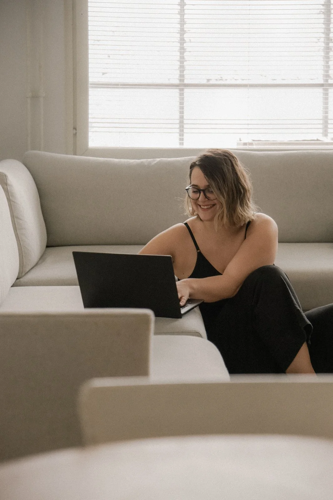 Nainen naputtelee tietokonettaan kotisohvalla.