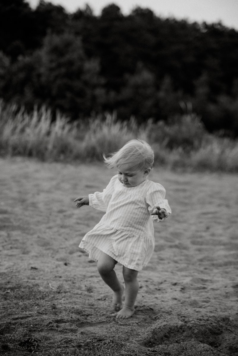 Pieni lapsi kävelee rannalla mustavalkokuvassa.